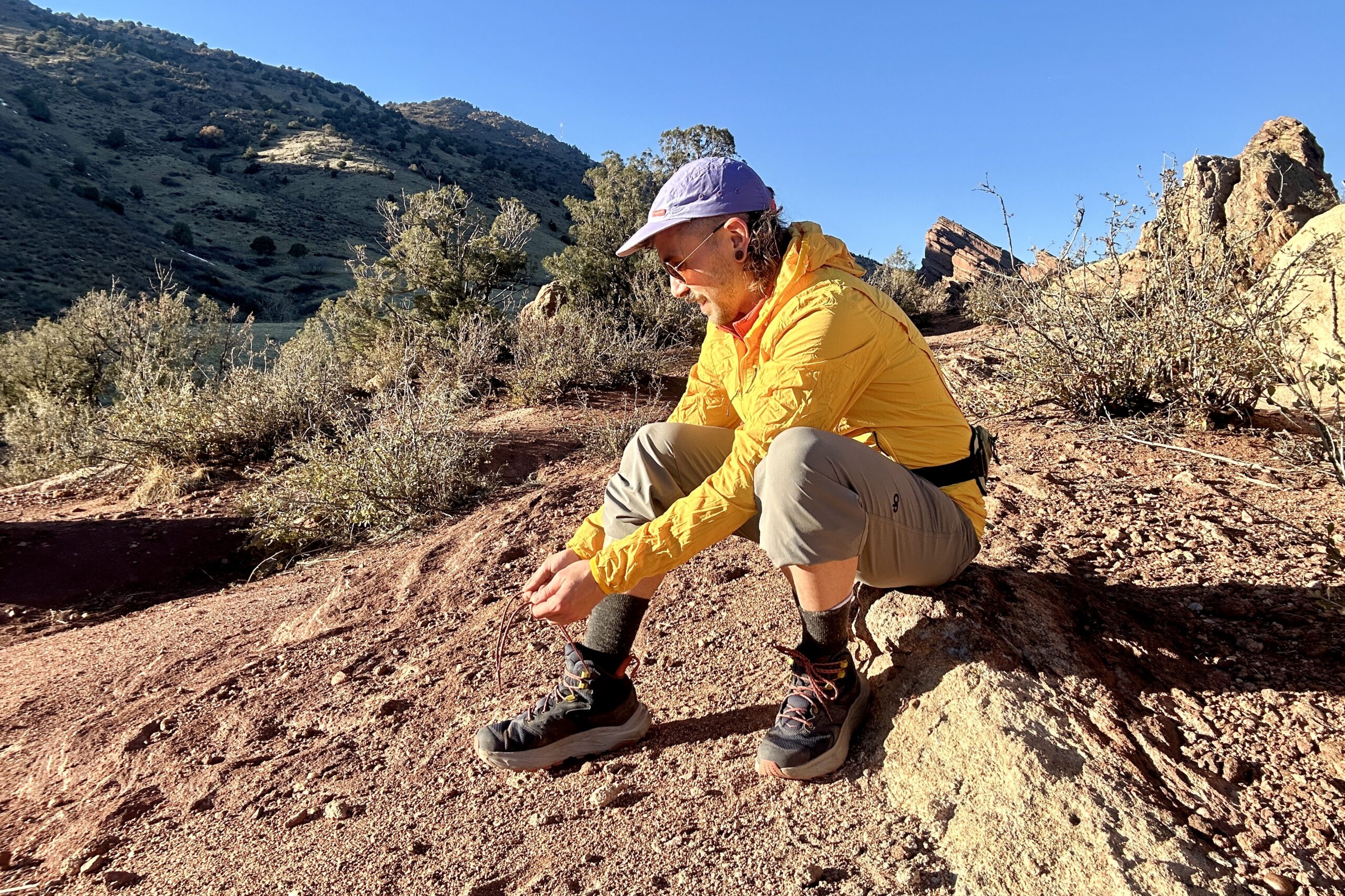 A man sits on a rock tying his boots.