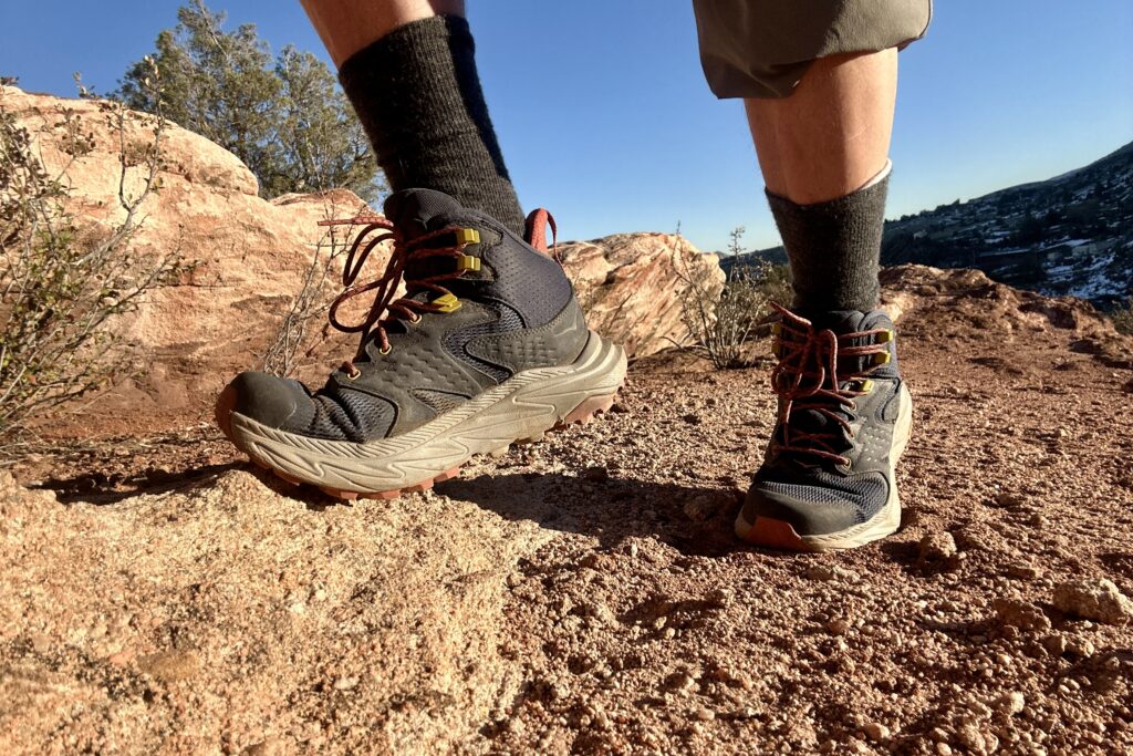 Close up from knees down of a person walking in hiking boots in a desert setting.