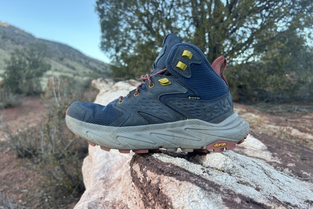 Close up of a single hiking boot posed on a rock facing left.