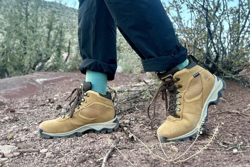 Close up from knees down of a person walking in hiking boots in a desert setting.