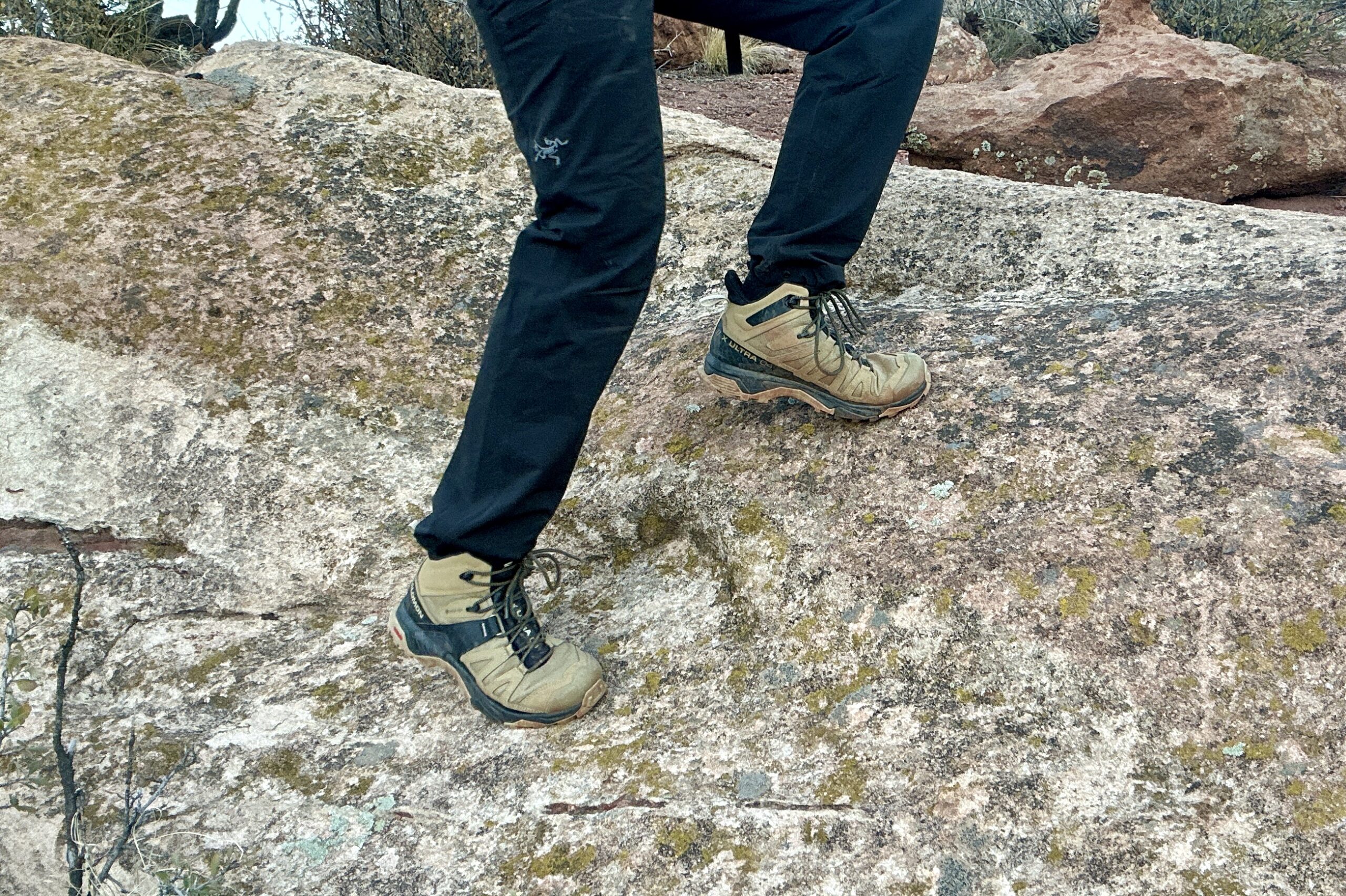 Close up from knees down of a person walking in hiking boots on a rock.