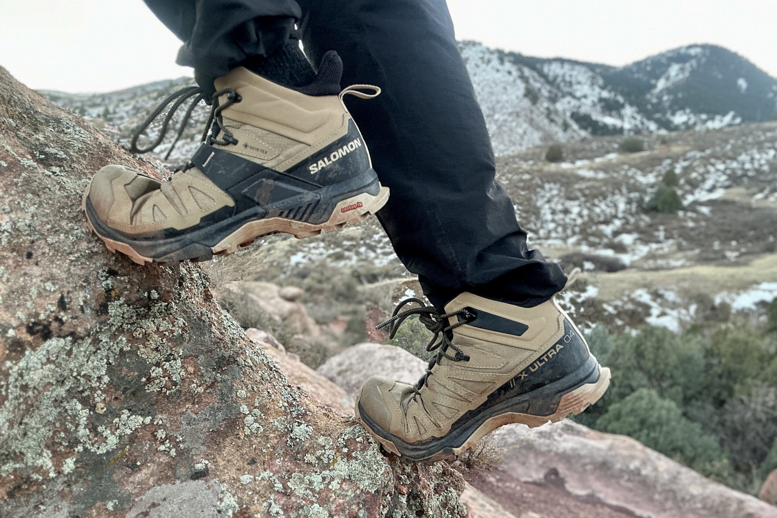 Close up from knees down of a person walking in hiking boots on a rock.