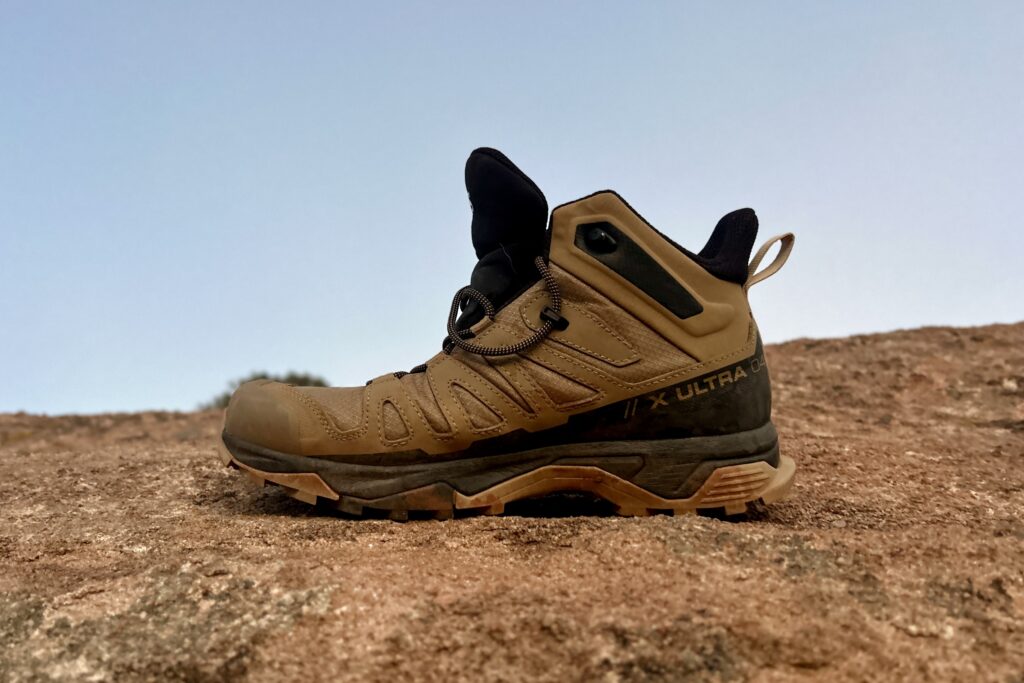 Close up of a single hiking boot posed on a rock facing left.