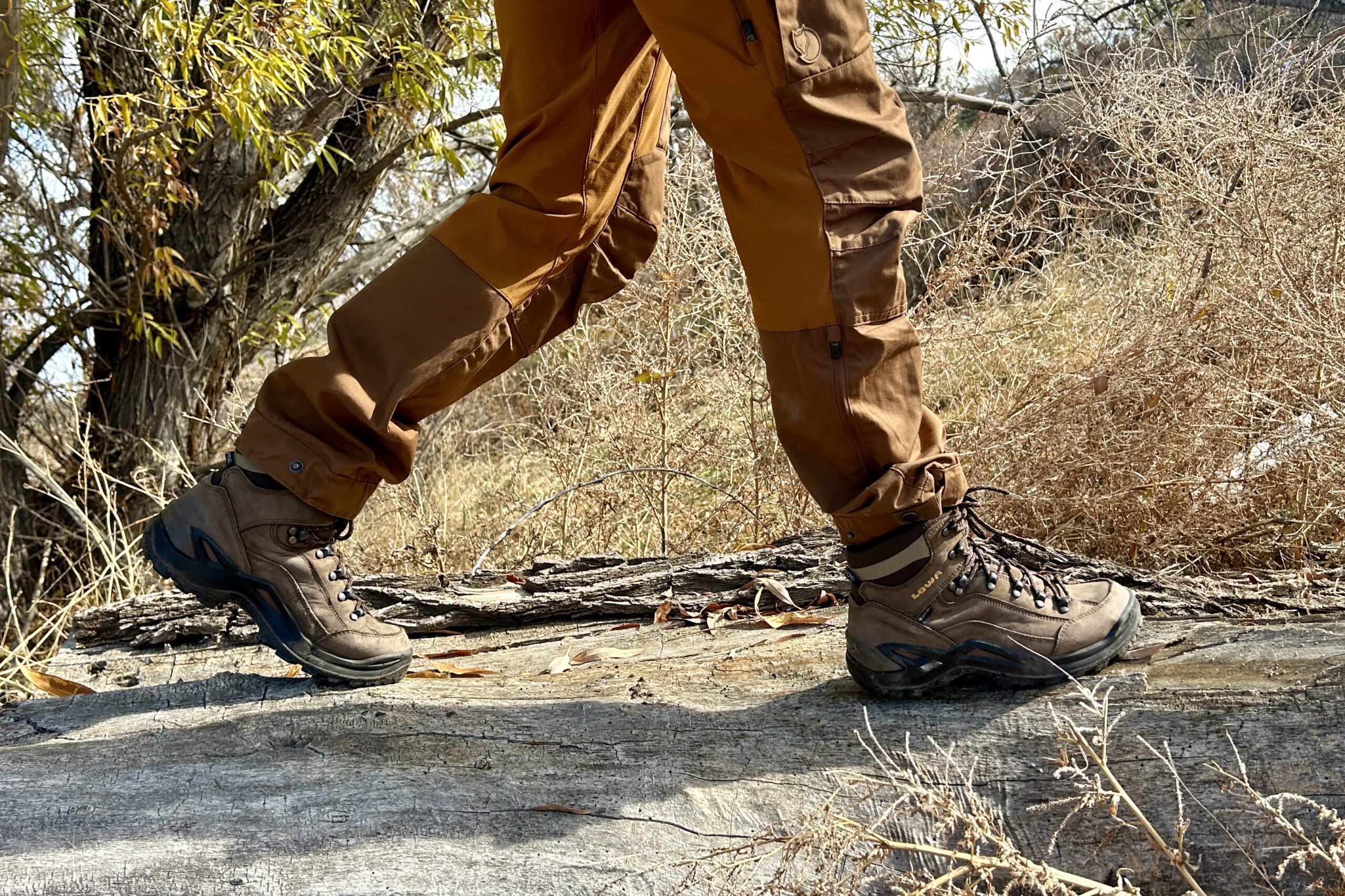 Close-up image from the knees down of a person walking in hiking boots in a wilderness area.