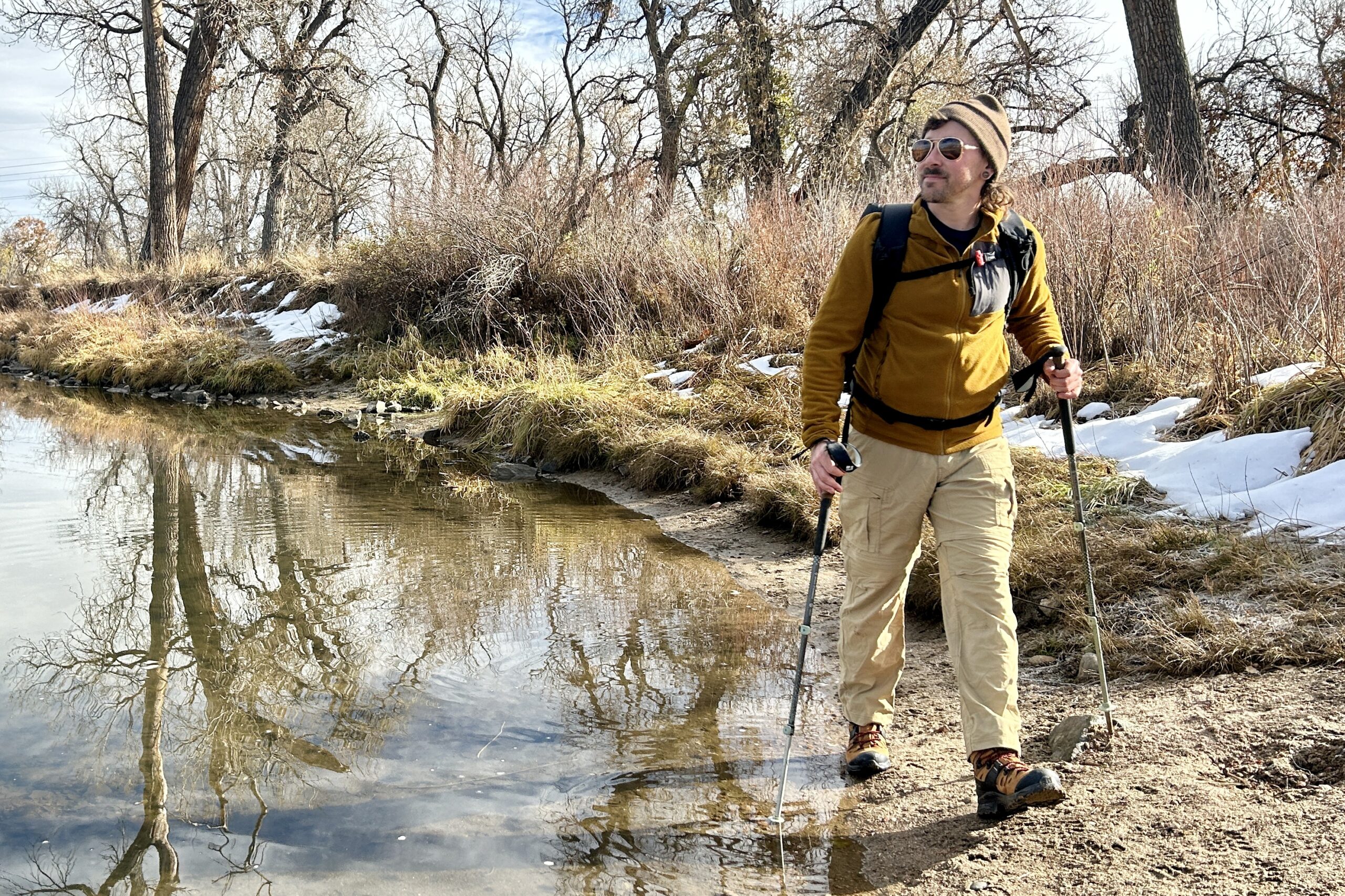 A man hikes along a river in a wilderness area on a cold fall day.