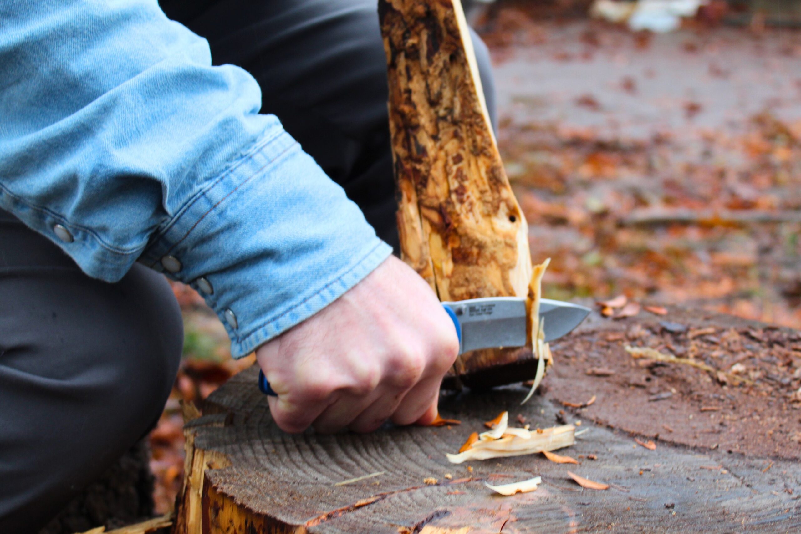 Using the Kershaw Blur pocket knife to cut shavings off a piece of fire wood