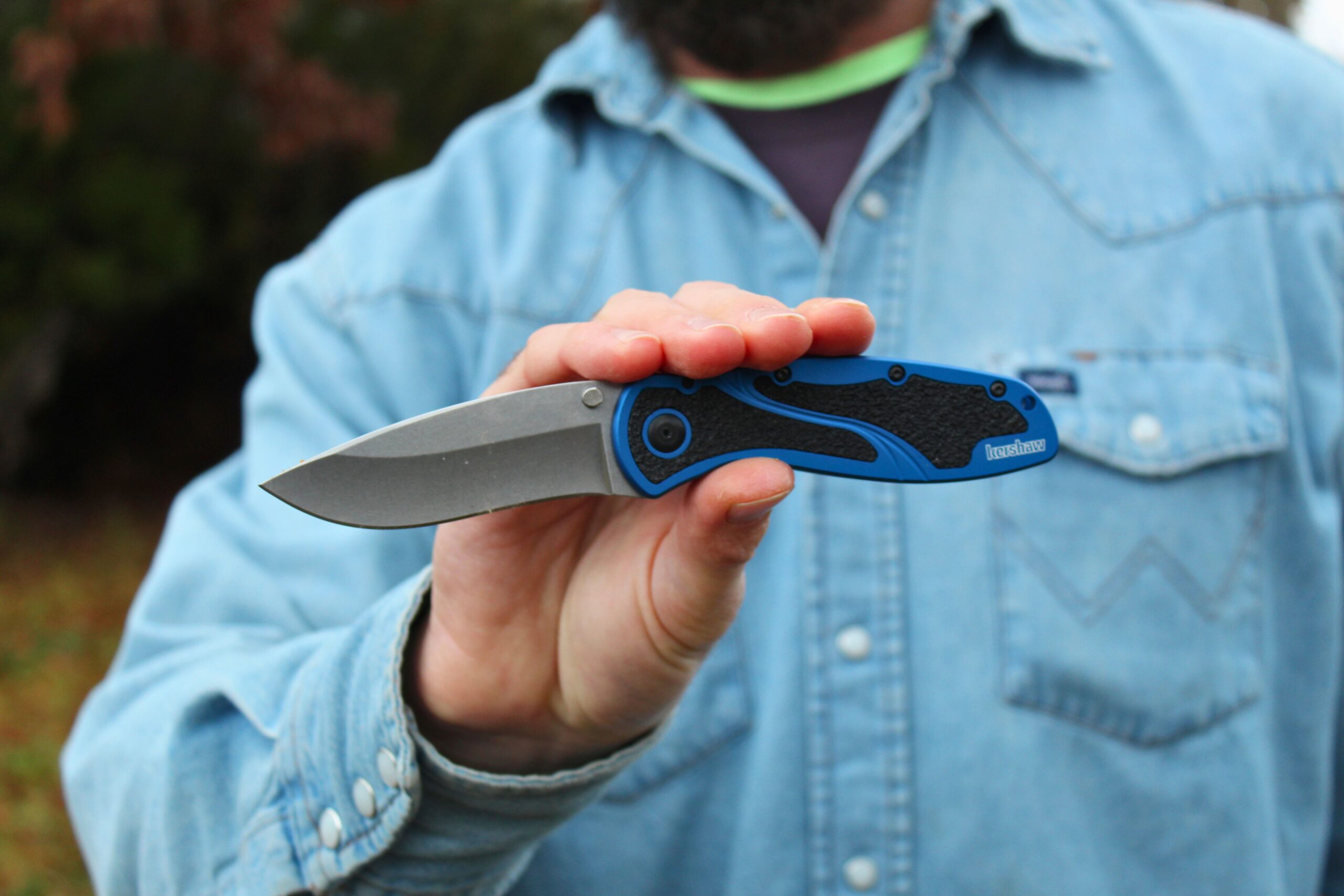 Man holding the Kershaw Blur pocket knife in front of him while it is open to show size.