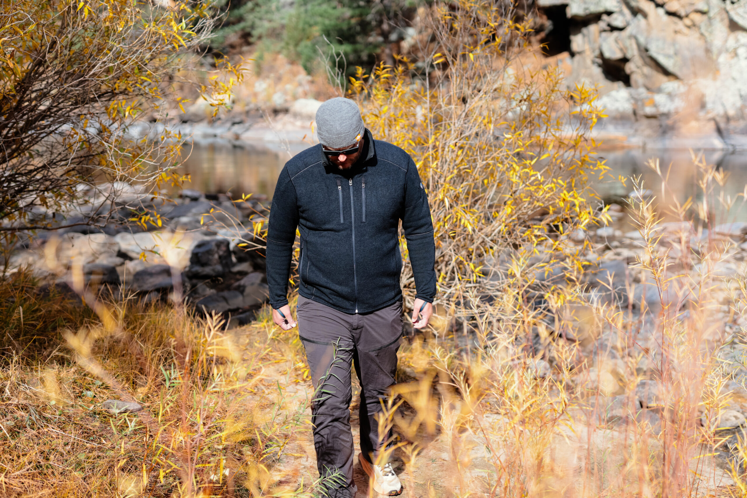 A man hikes along a river bank.