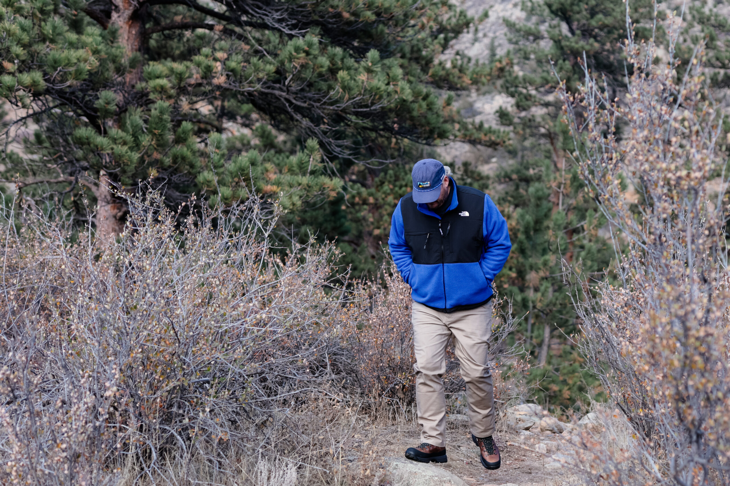 Man walks down a trail in a blue fleece.