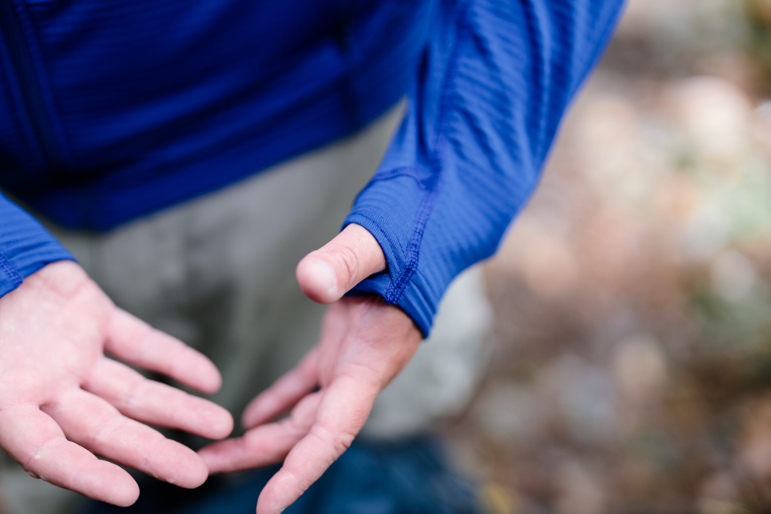 a close up of a man's hands with his thumb through the fabric hole on the Outdoor Research Vigor Fleece Jacket