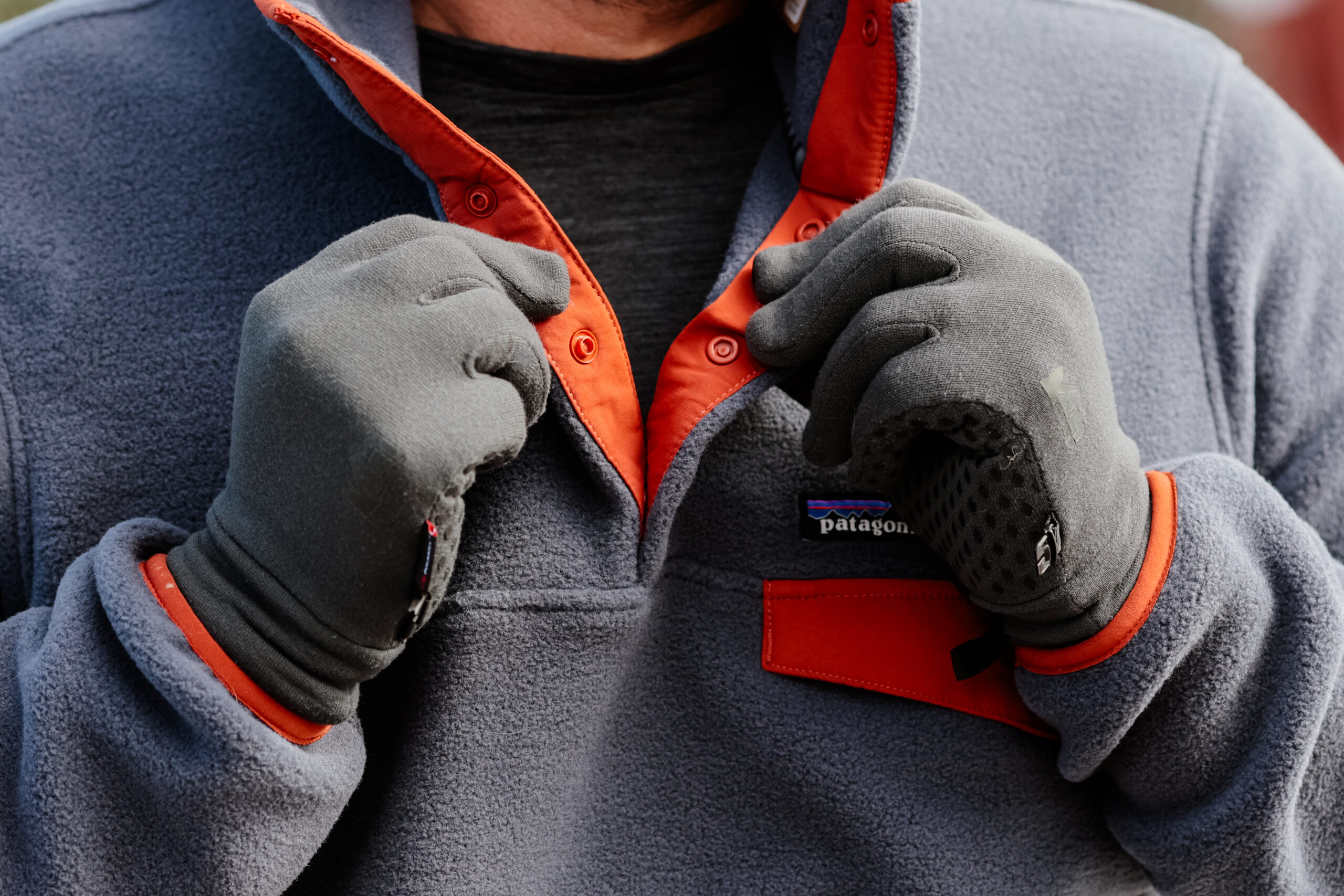 A man's hands hold the snaps on a fleece.