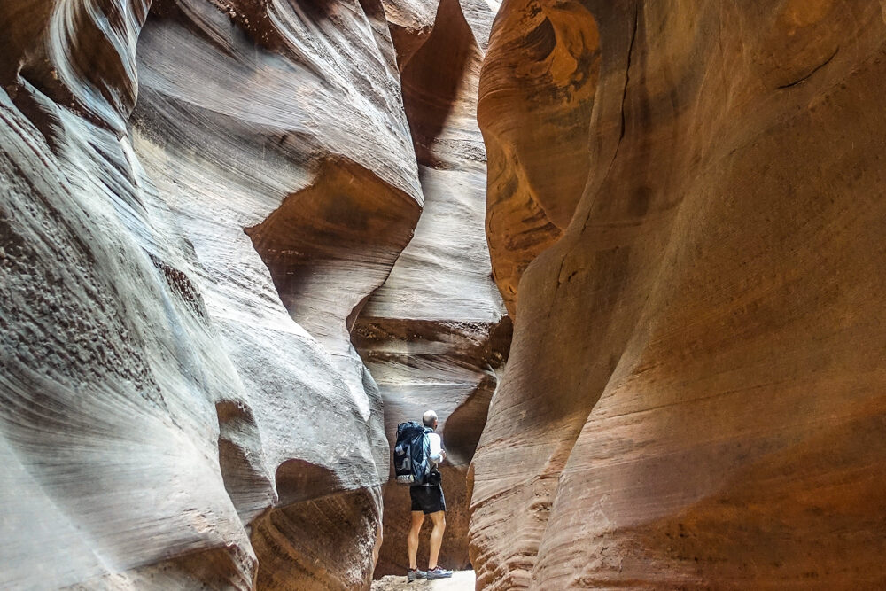 a hiker walks in a slot canyon