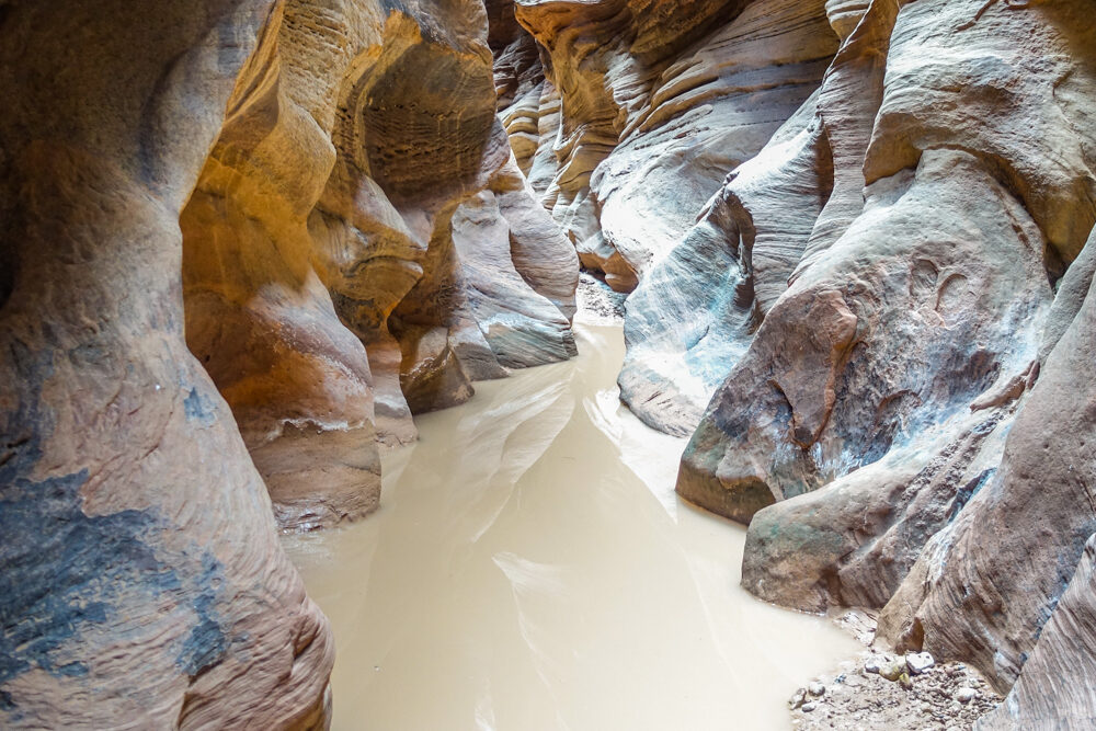 a brown pool of water in the paria slot canyon