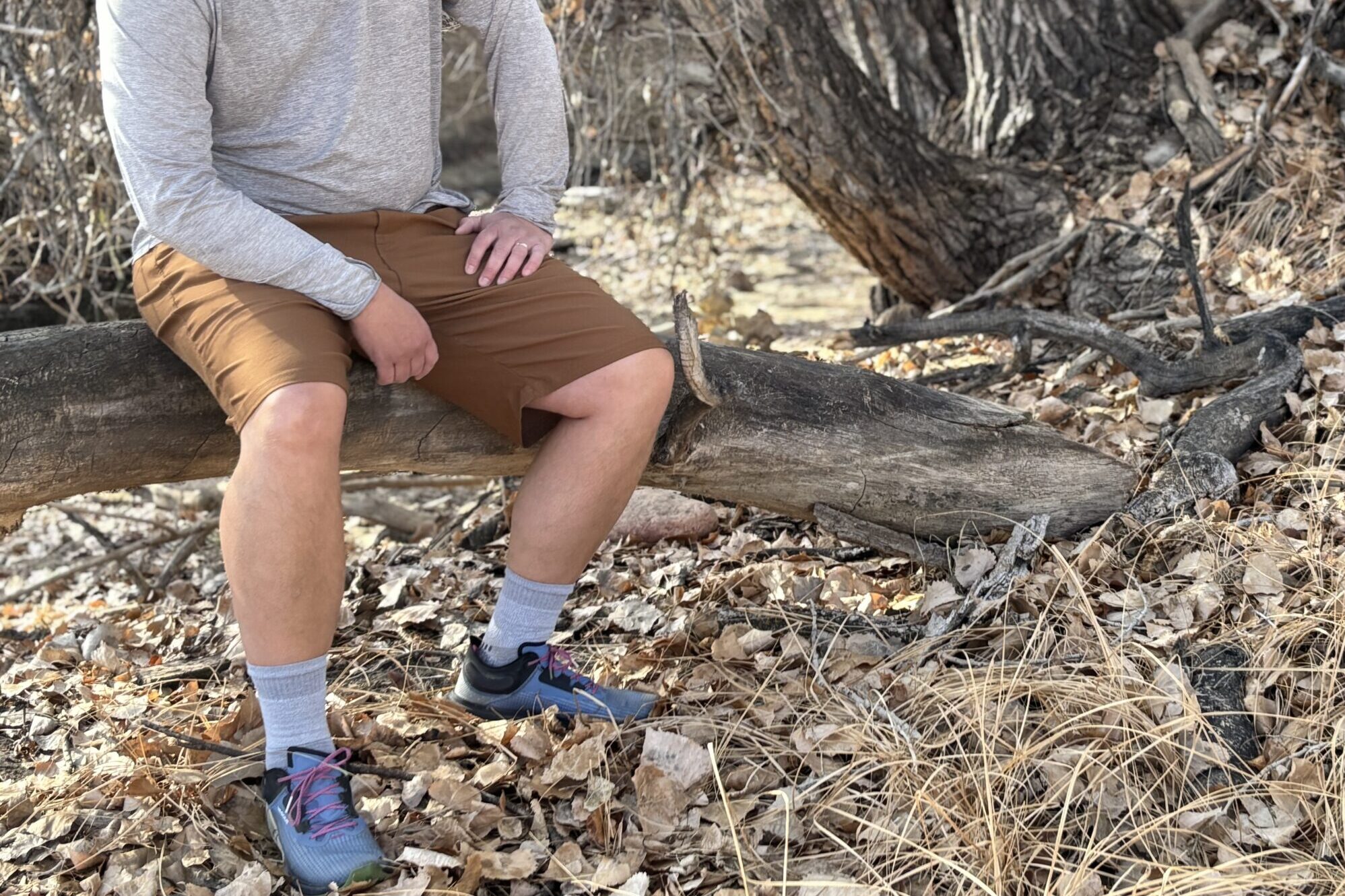 Man sitting on a log in shorts.