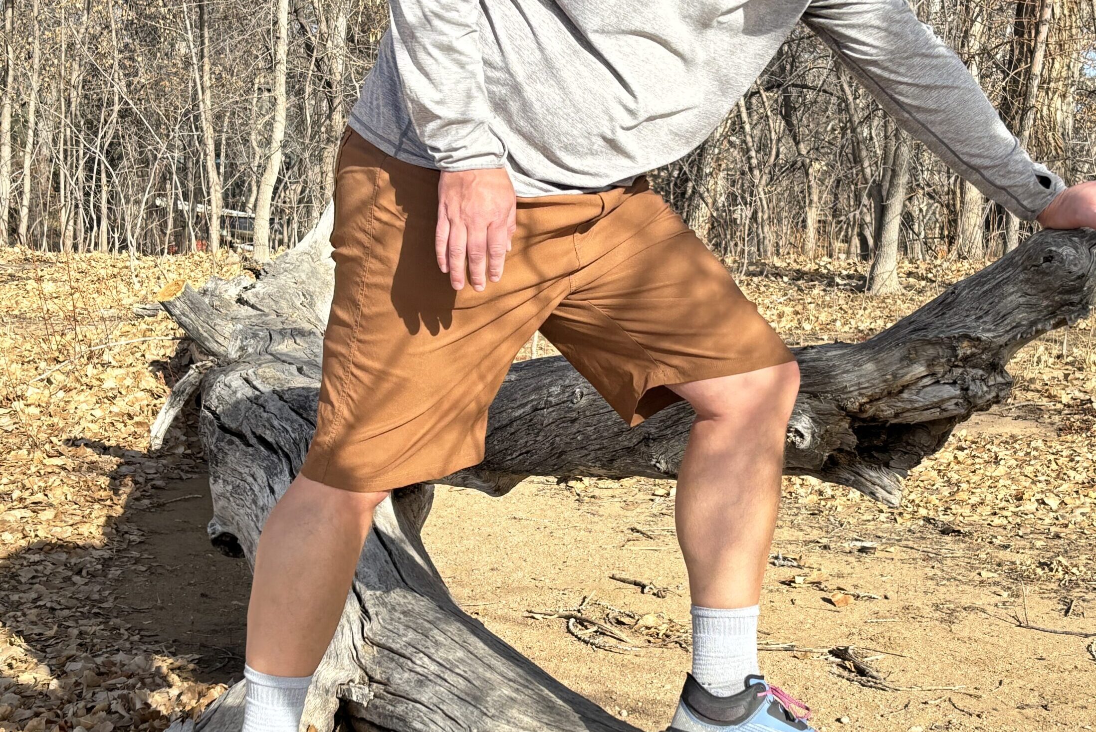 Man steps over log in shorts.