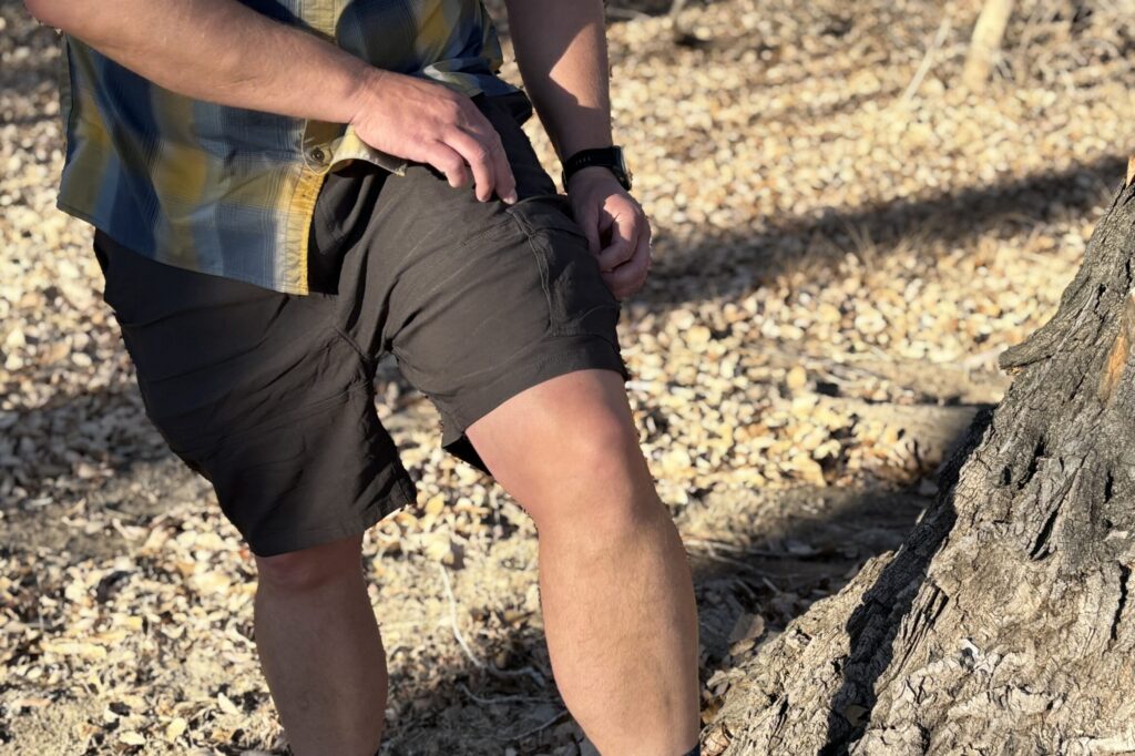 Man wearing shorts steps on a tree.