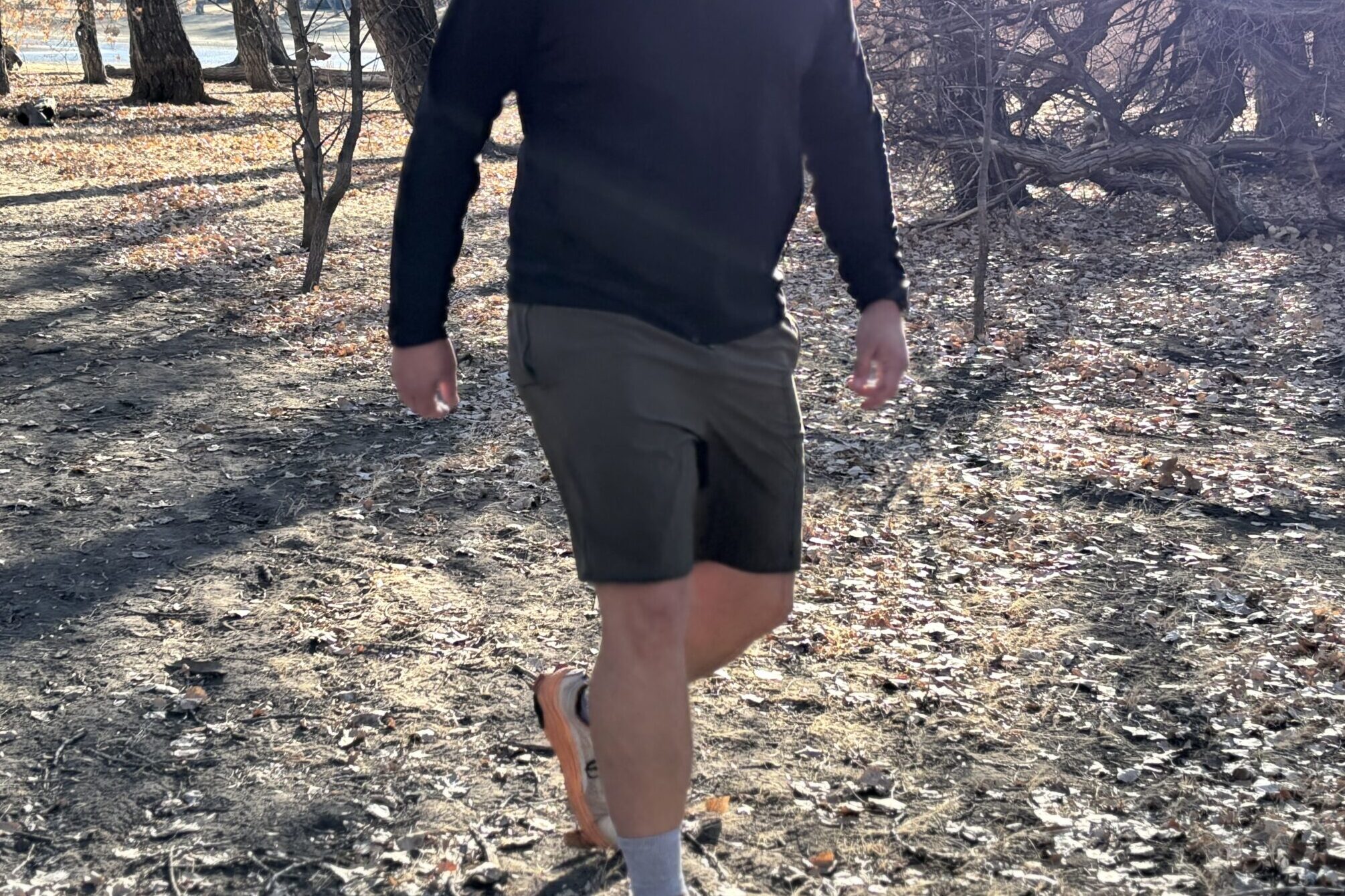 Man walking in shorts through the woods.