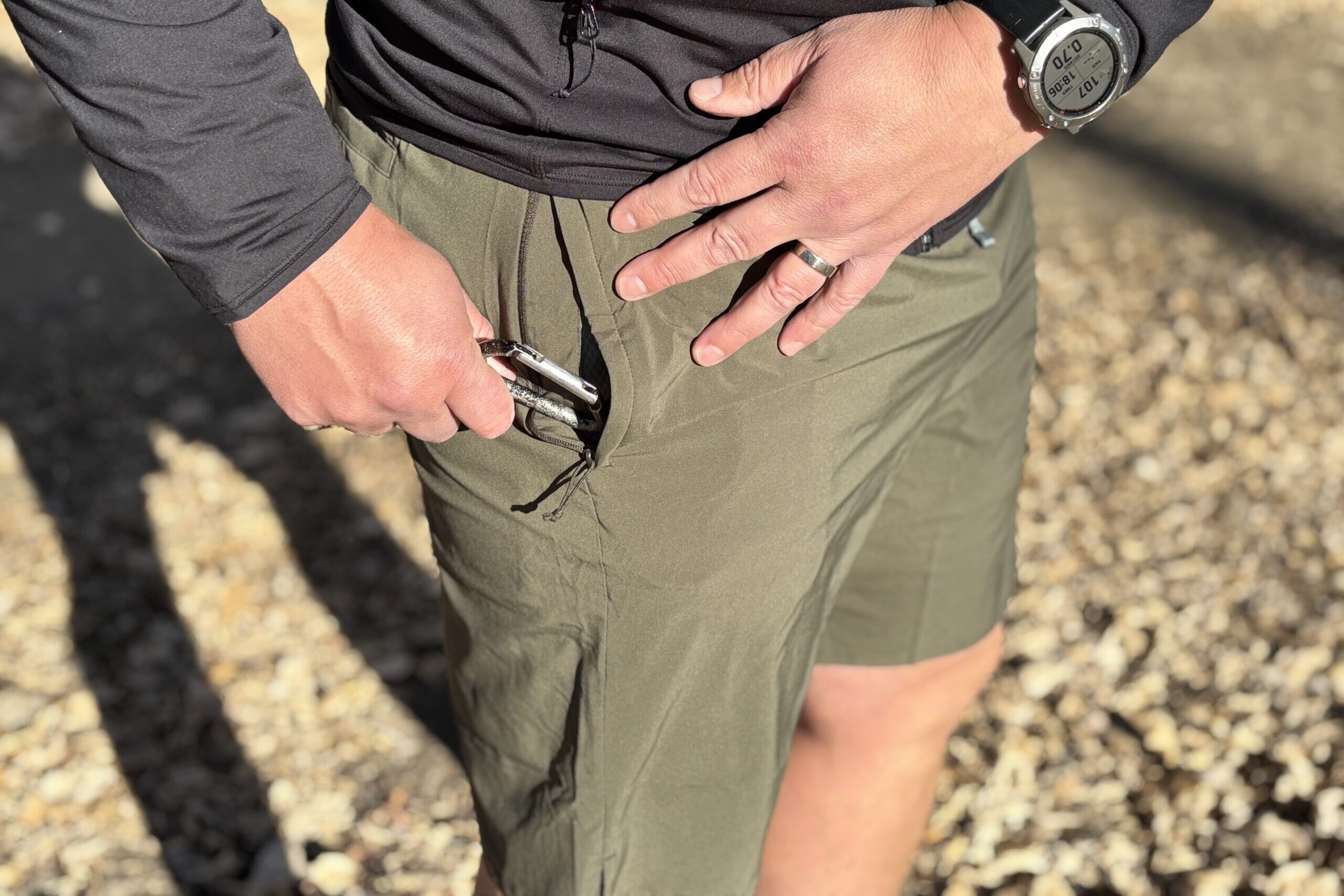 Man pulls a carabiner from his pocket.