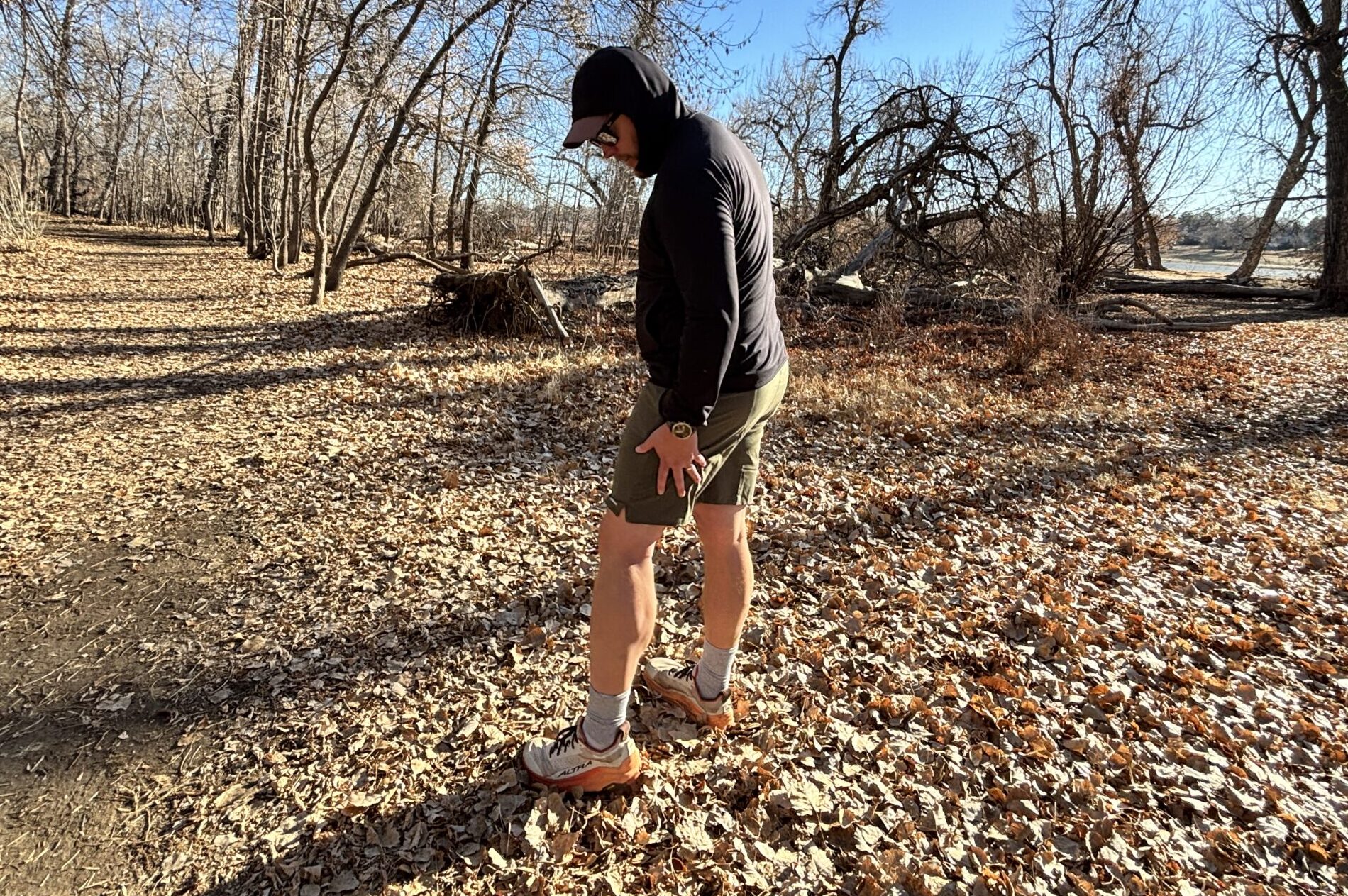 A man stands in the woods in shorts.