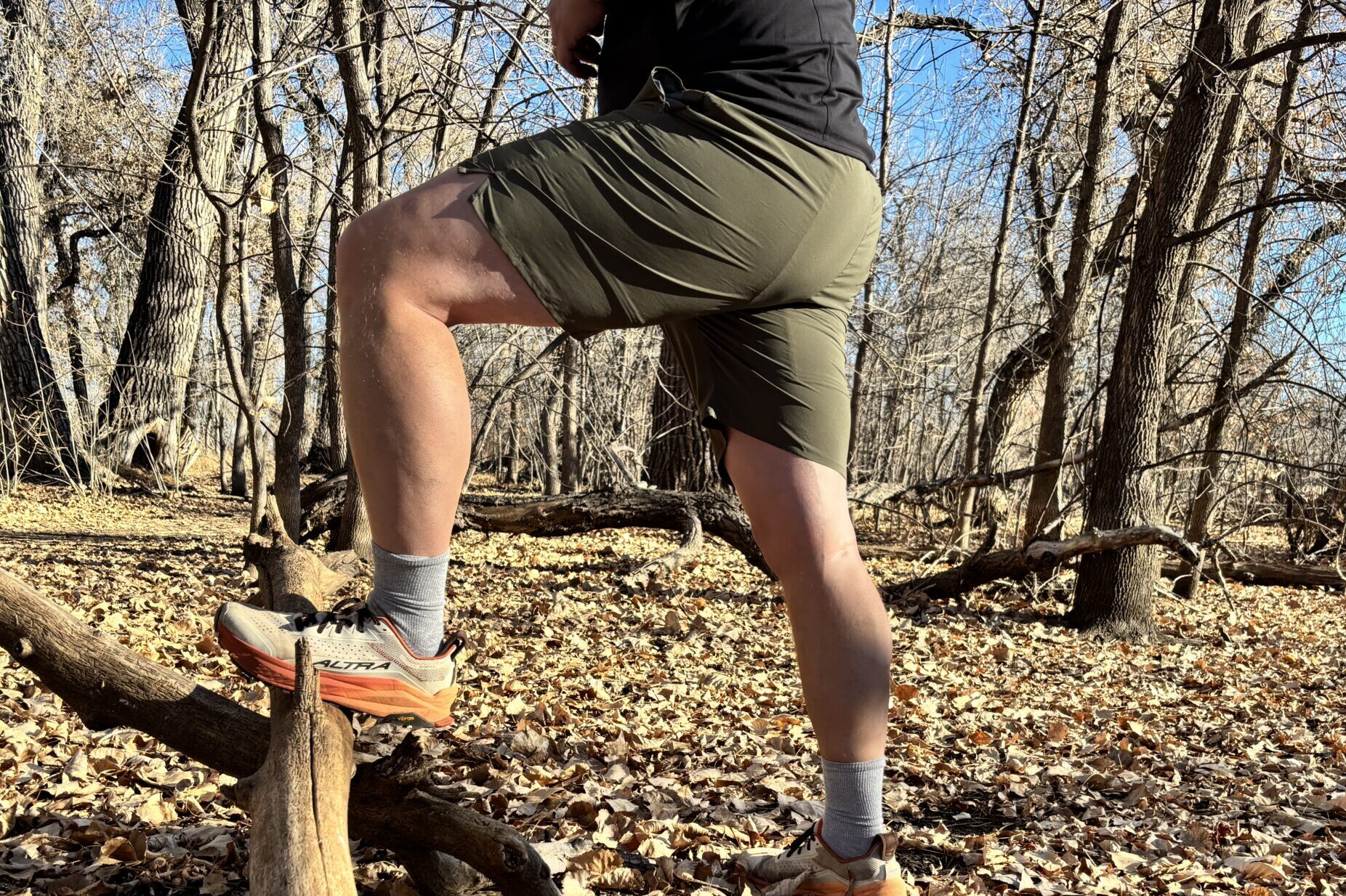 A man in shorts steps on a log.