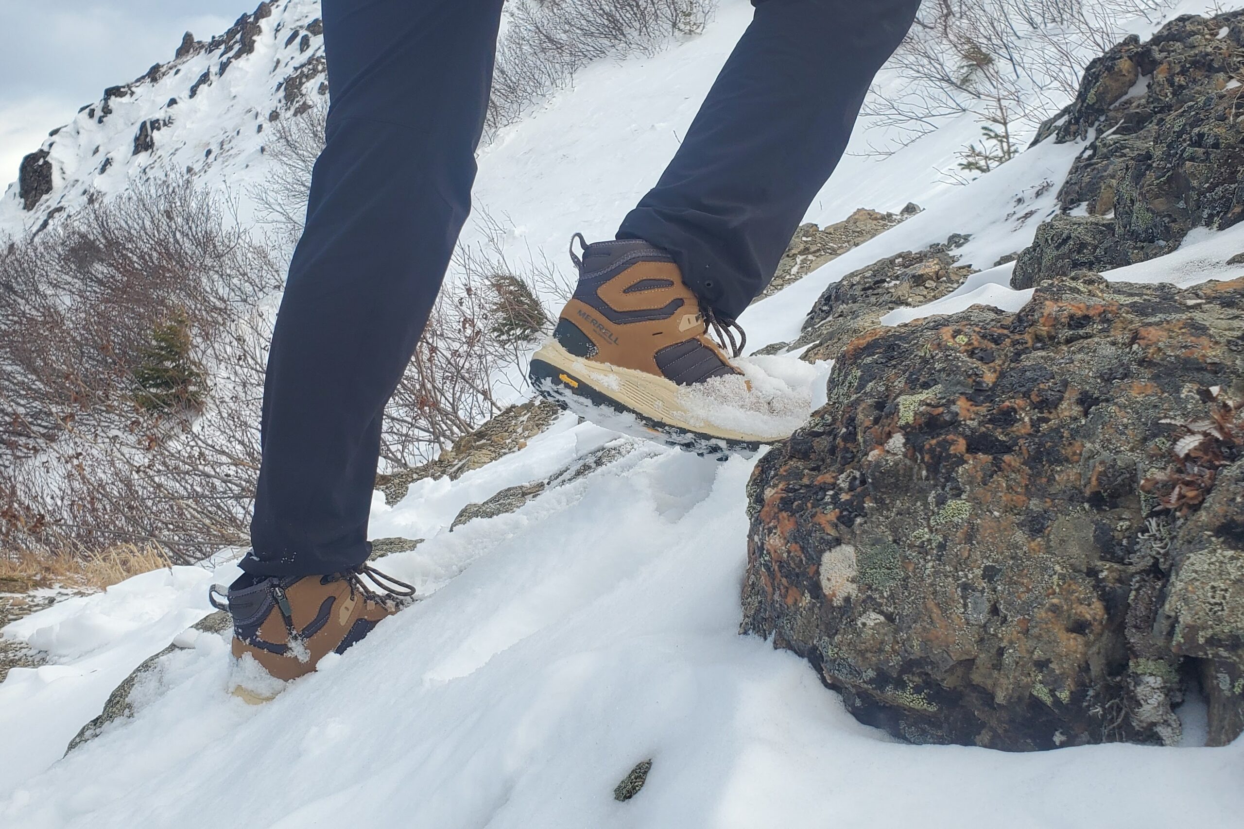 A closeup of winter boots hiking up a snowy slope.