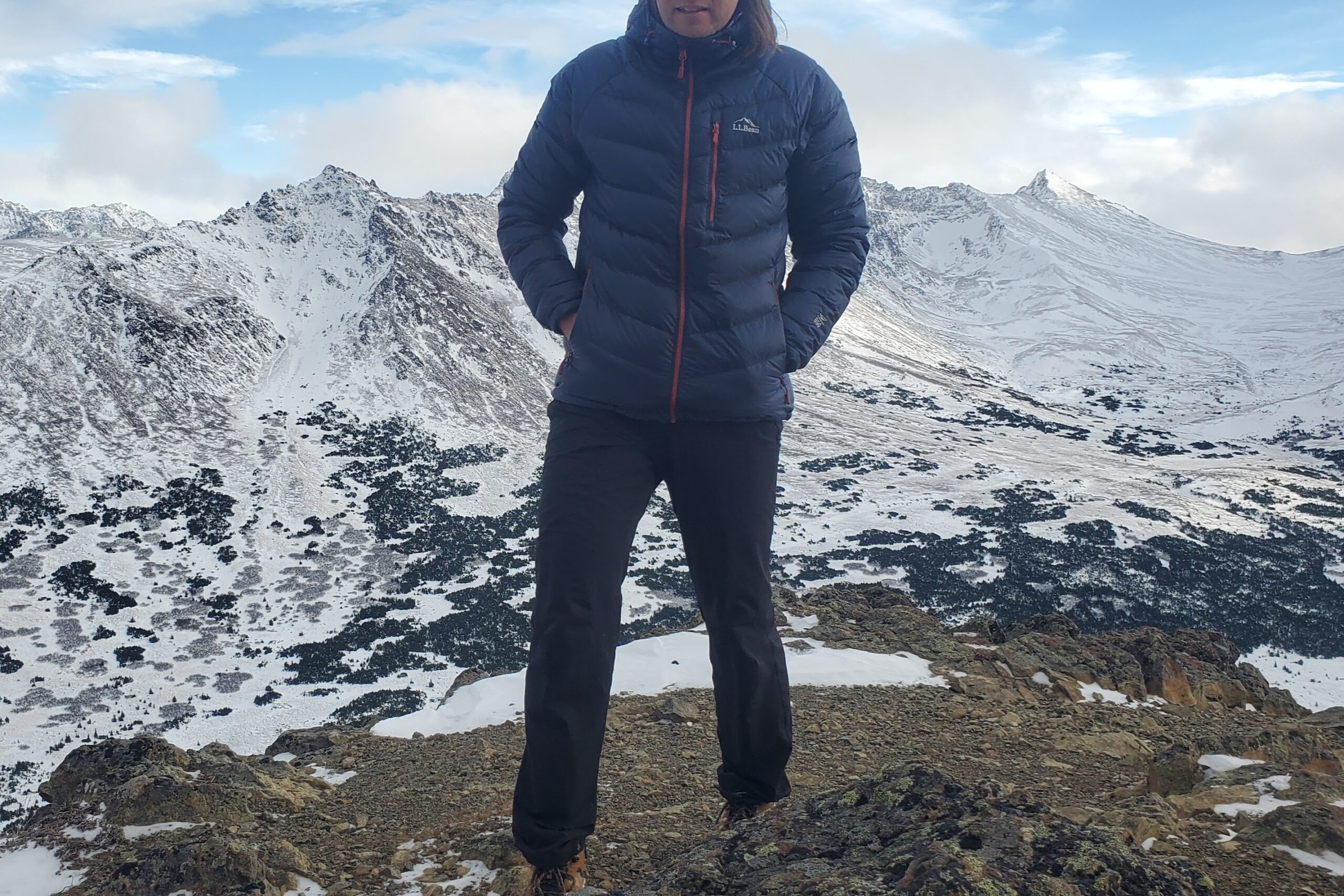 A man faces the camera on a wintery mountaintop