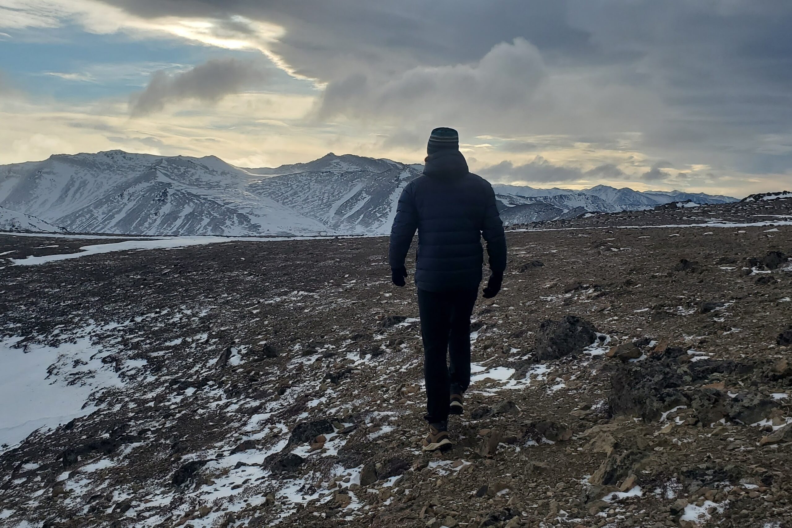 A man walks away from the camera on a mountaintop