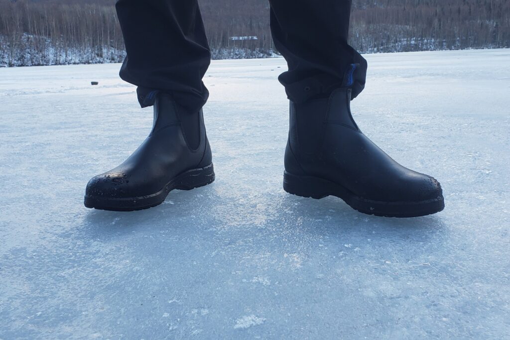 A pair of boots stands on a frozen lake.