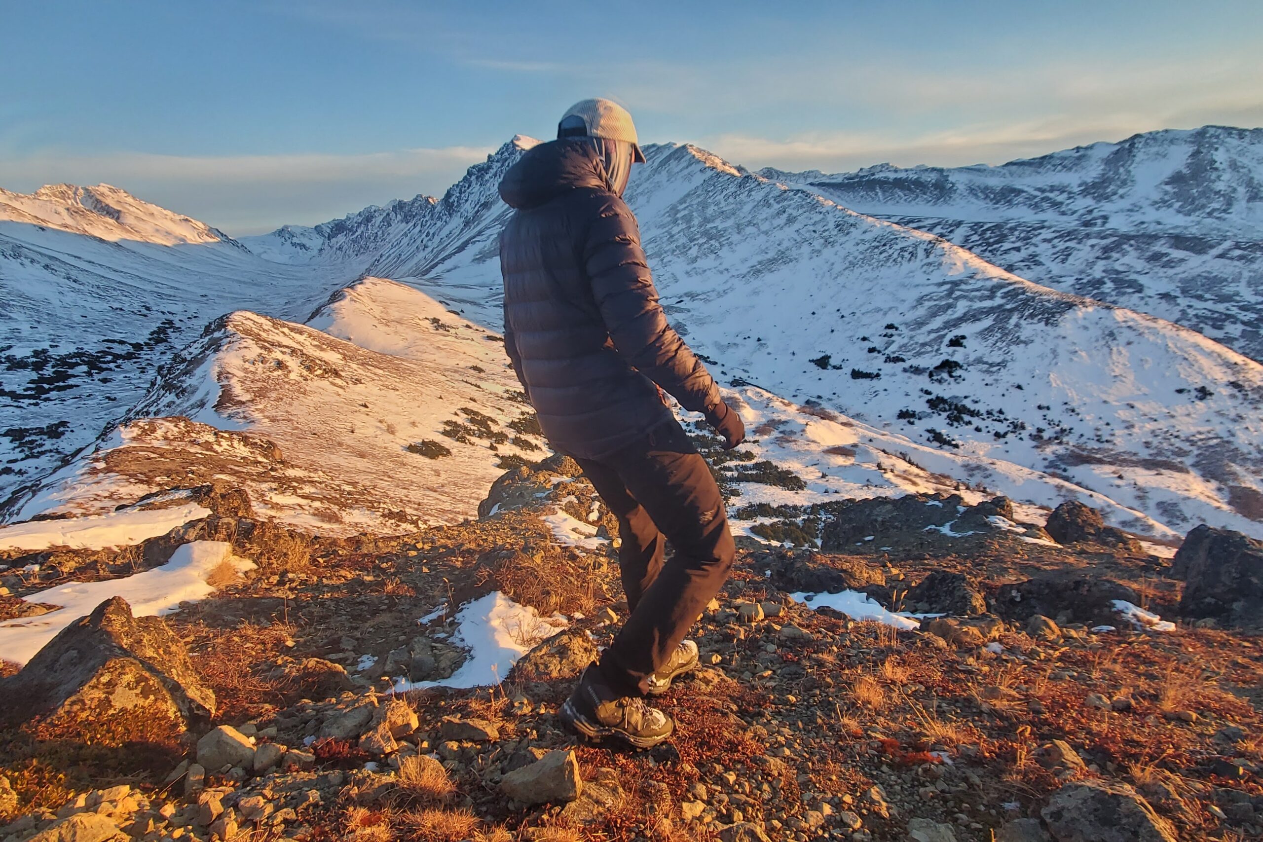 A man walks down a mountainside in evening light