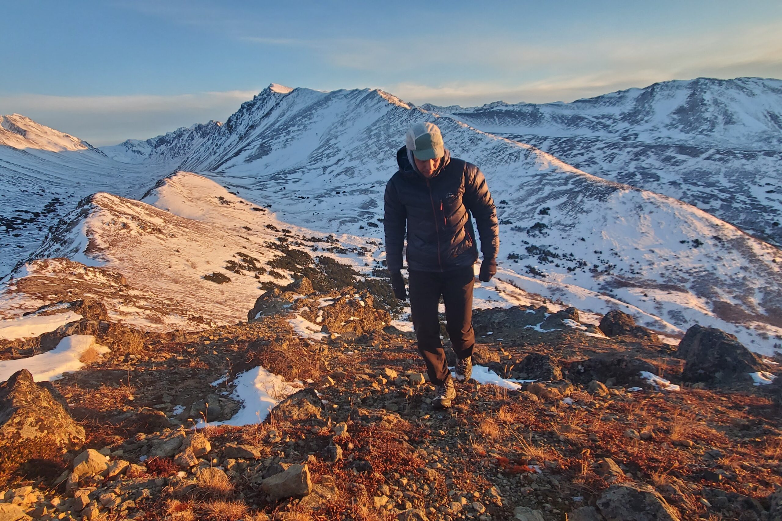 A man walks up a mountainside at sunset