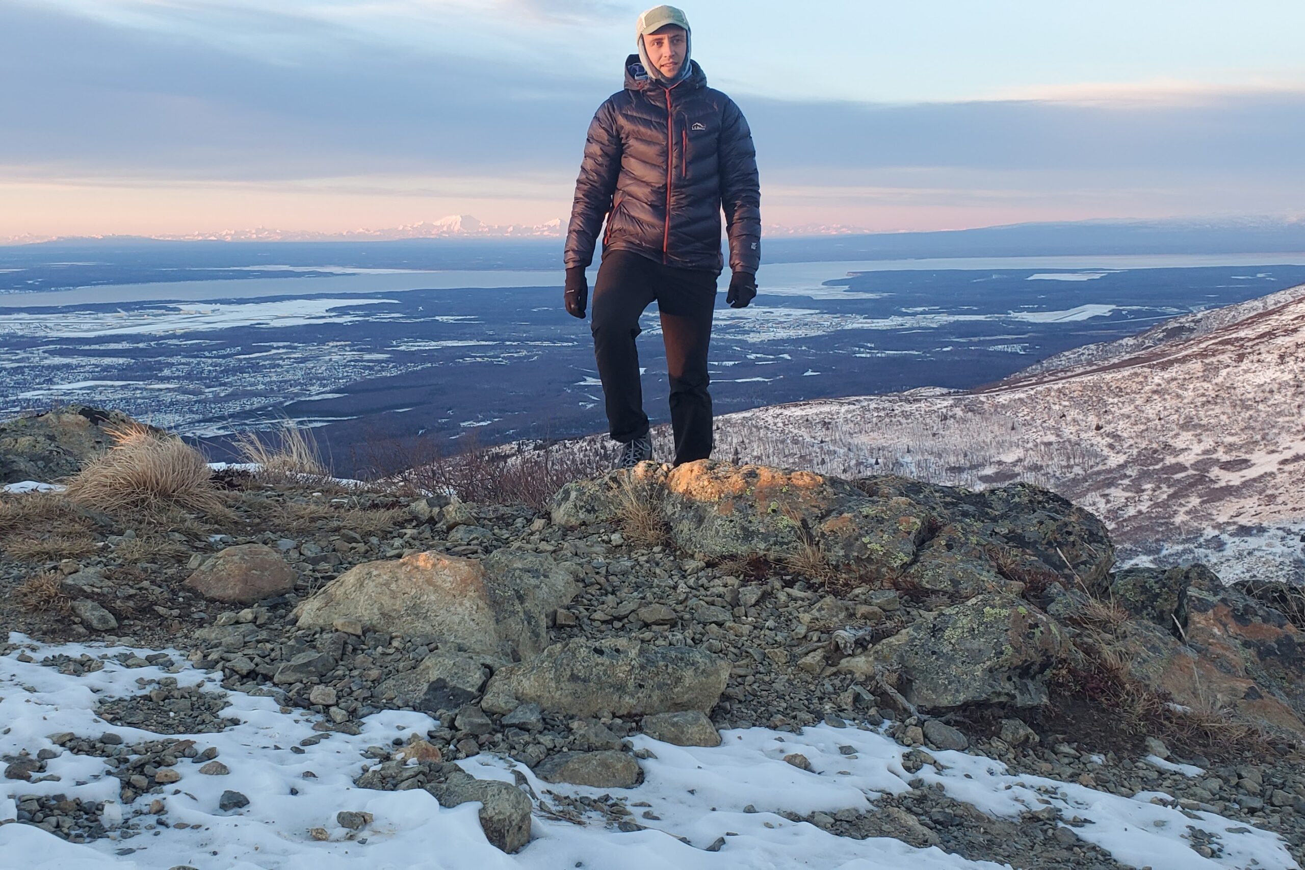 A man stands at sunset in front of a broad view