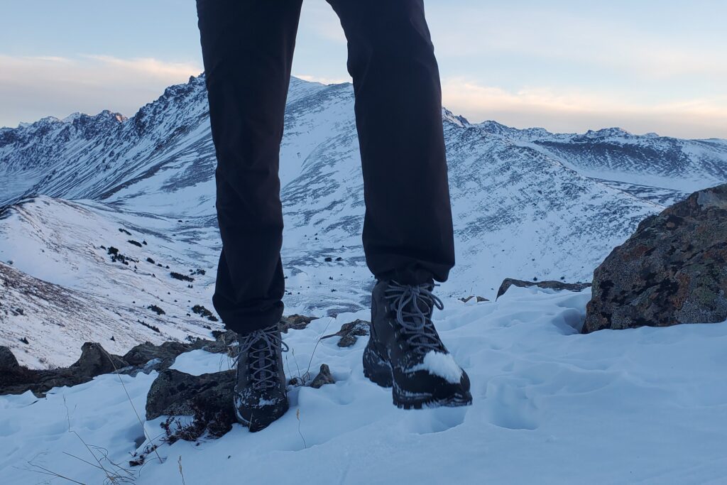 A man walks through snow in a mountainous landscape