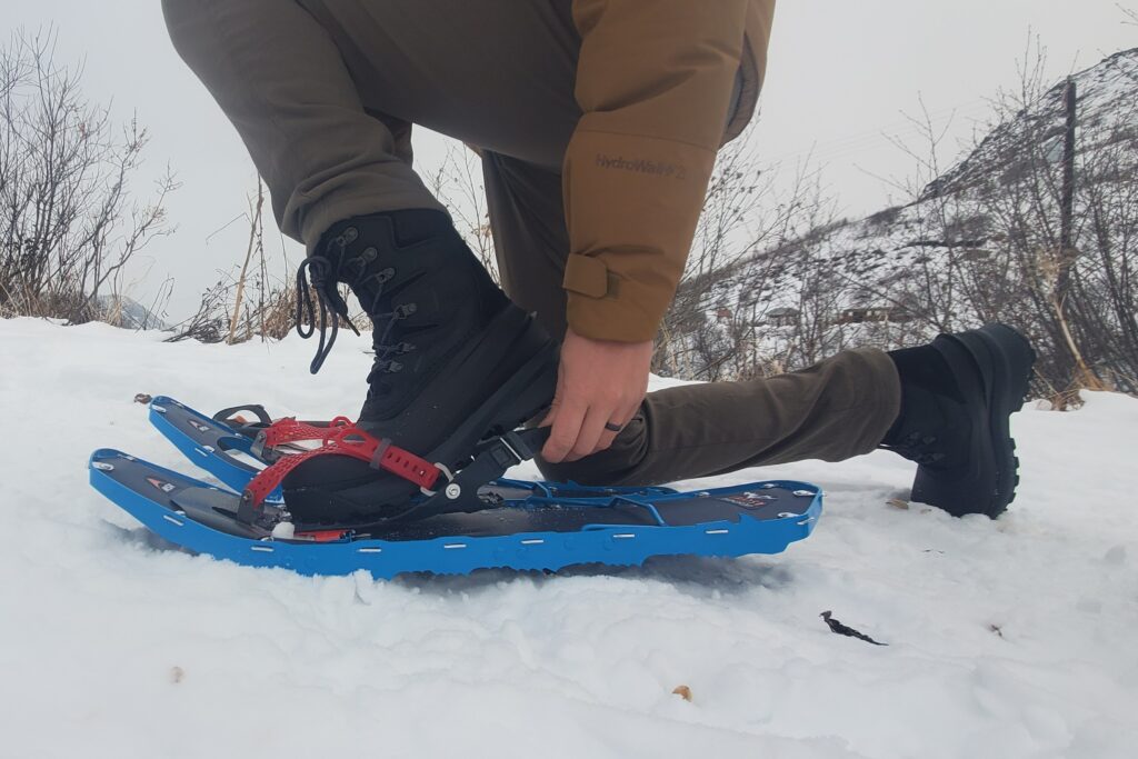 A man secures snowshoes to winter boots.