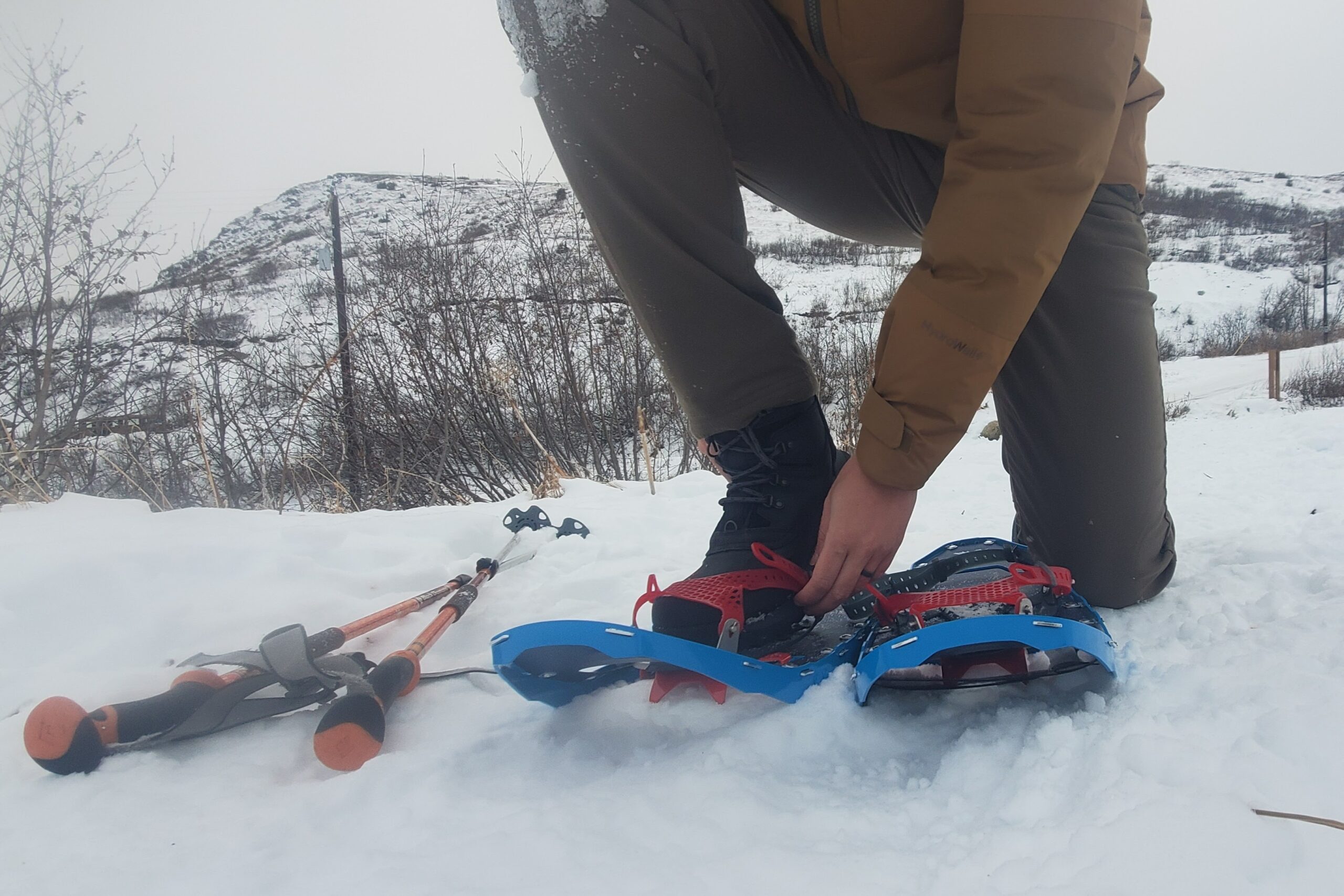 A man tightens the bindings of his snowshoes