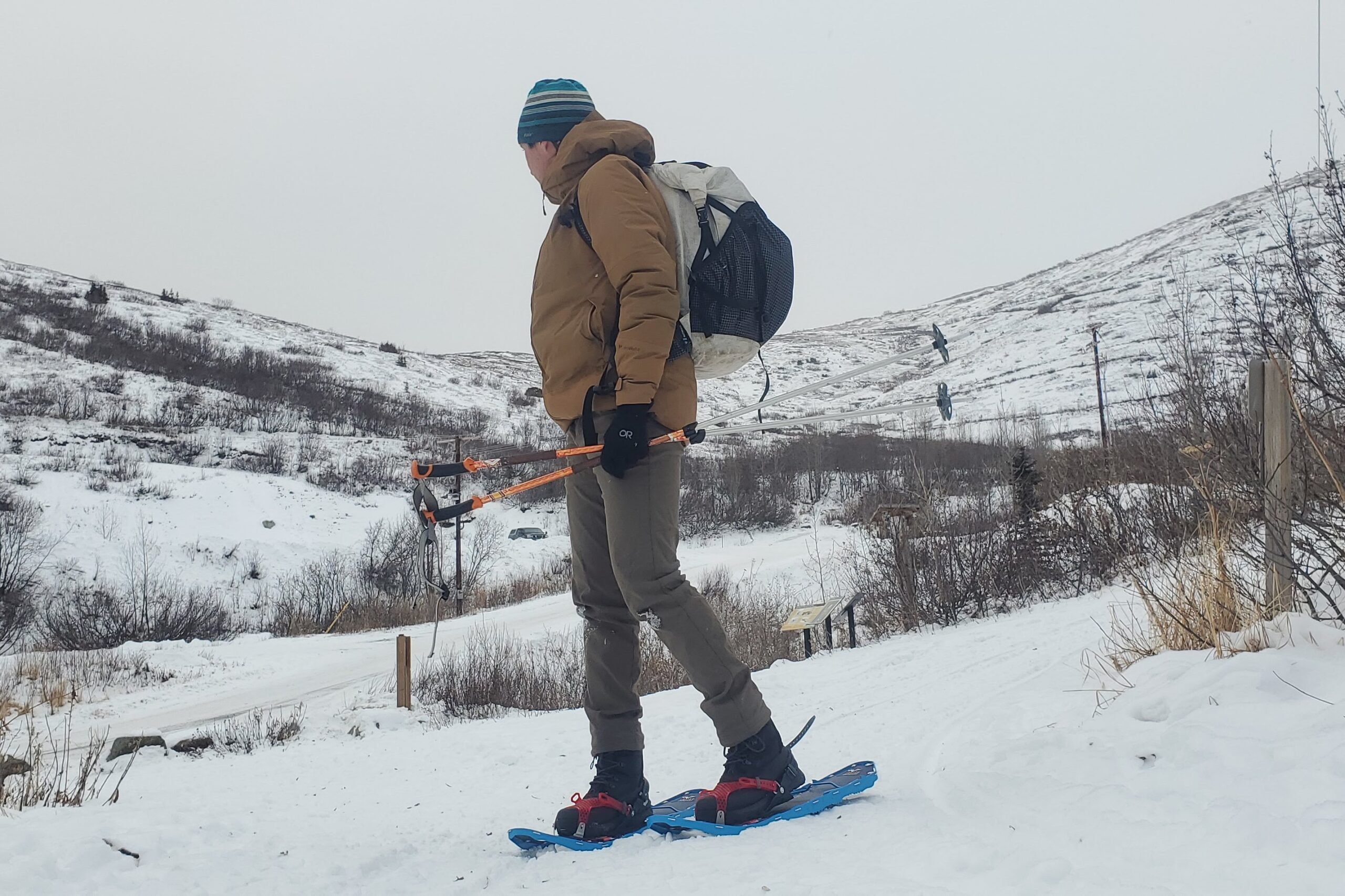 A man stands in snowshoes on a winter trail