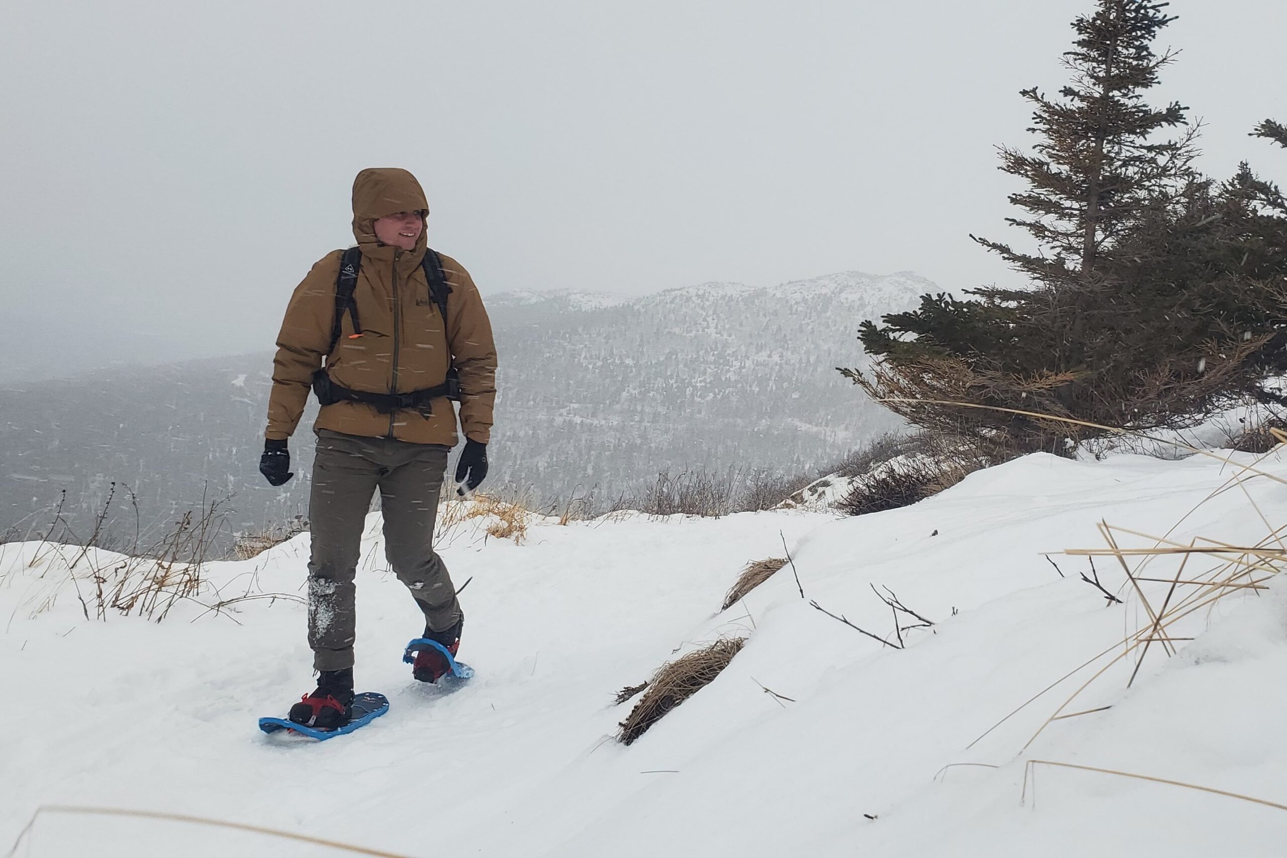 A man hiking on a trail in snowshoes.