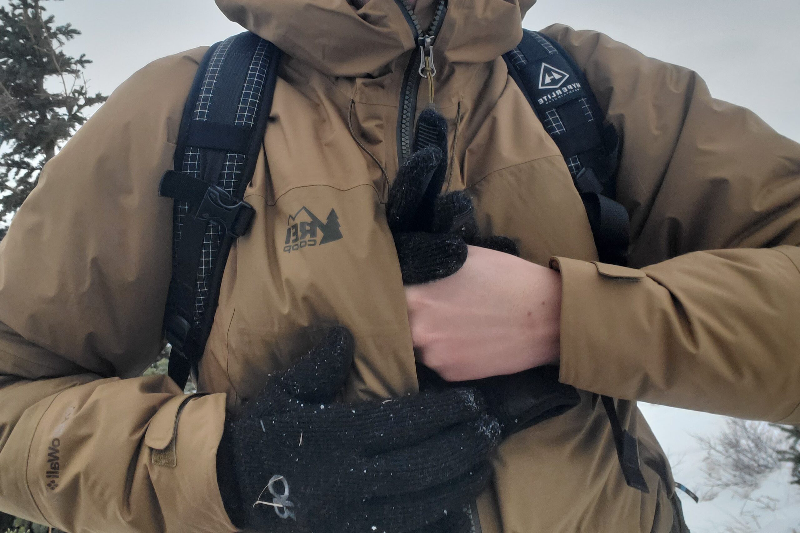 A man packs a pair of gloves into a chest pocket.