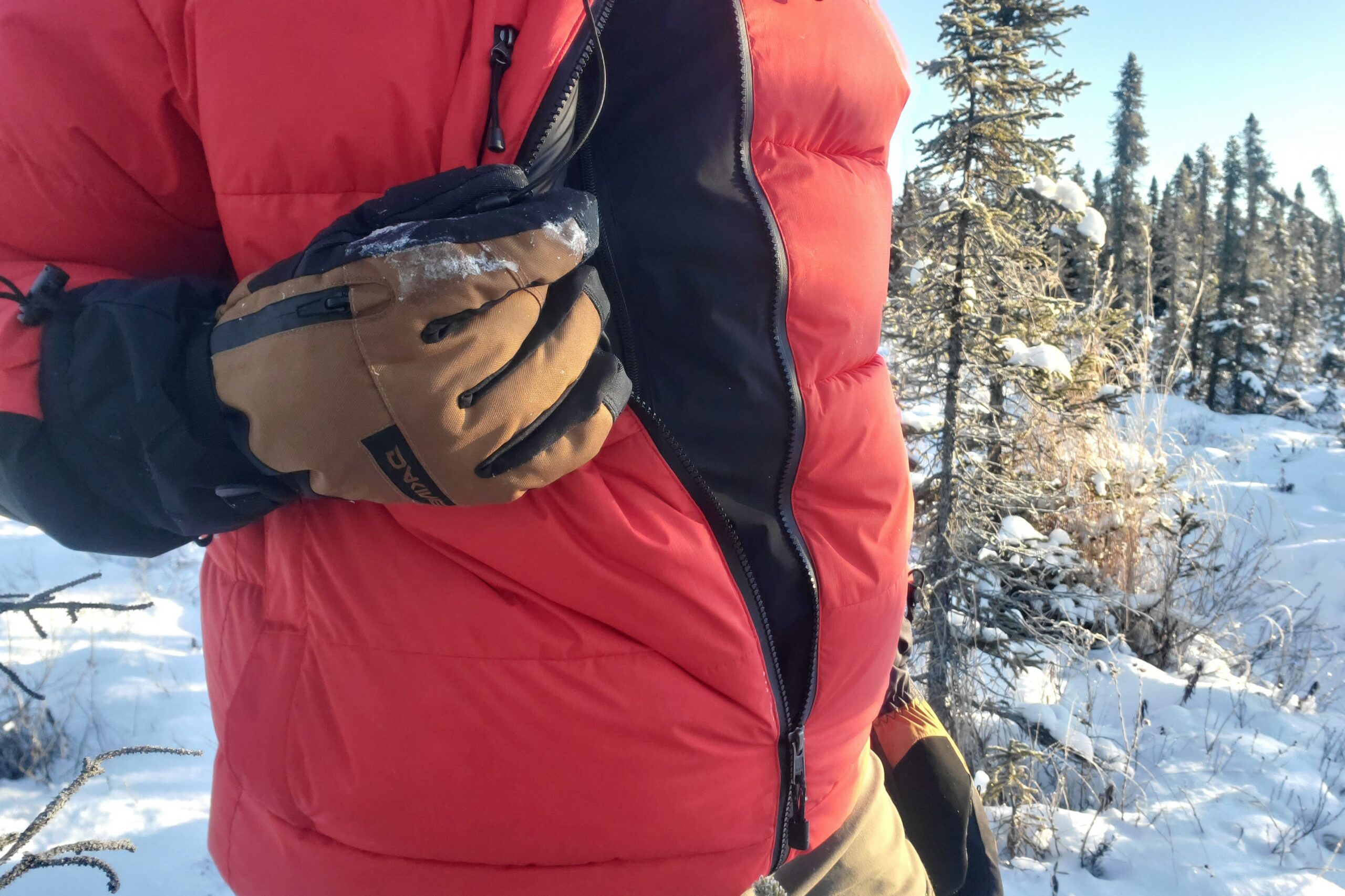 A closeup of gloves unzipping a jacket.