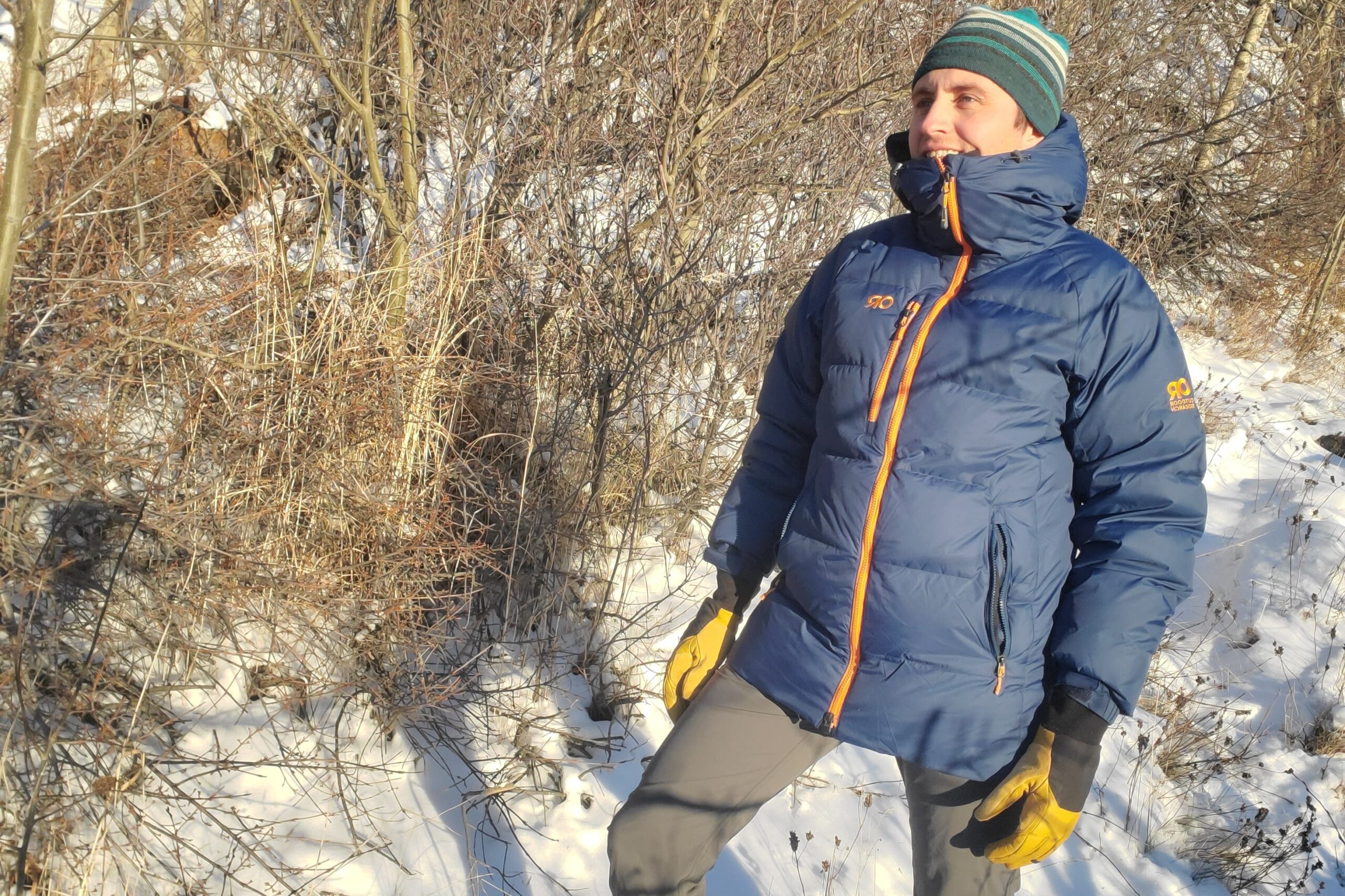 A man stands in a blue jacket on a winter trail.