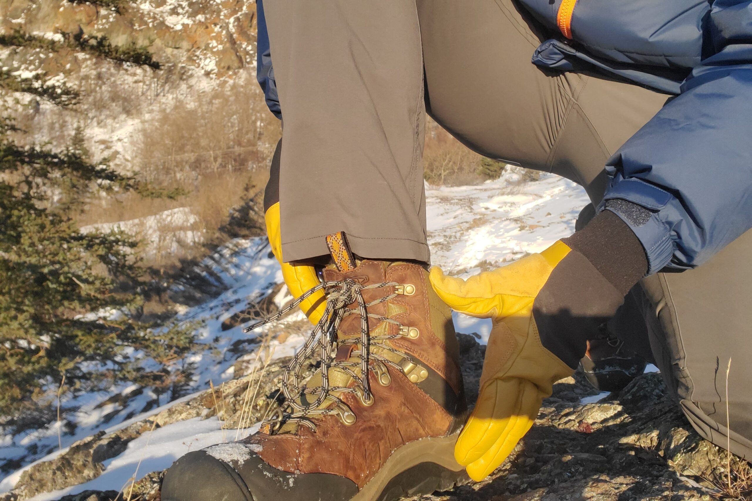 A closeup of a main wearing gloves tightening his boots.