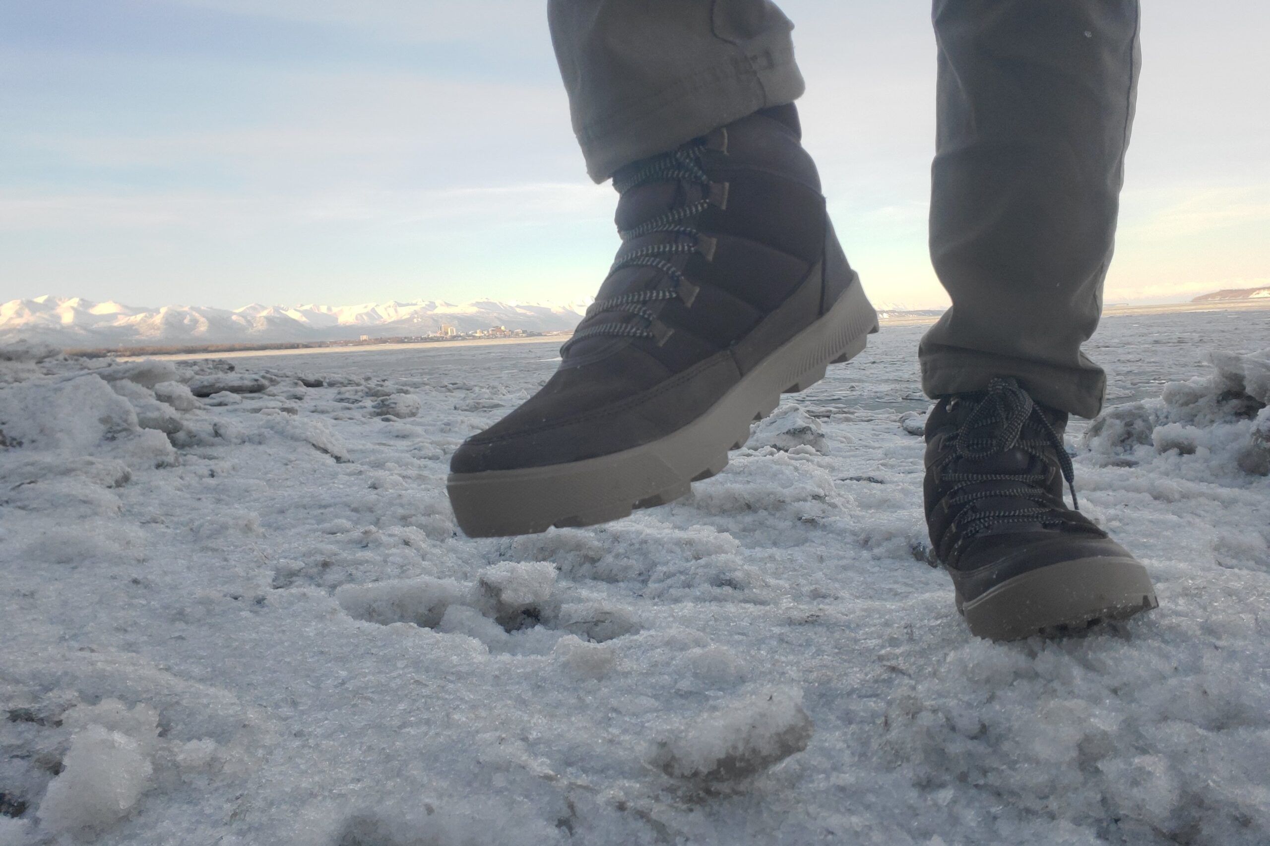 A closeup of a man taking a step over crusty ice.