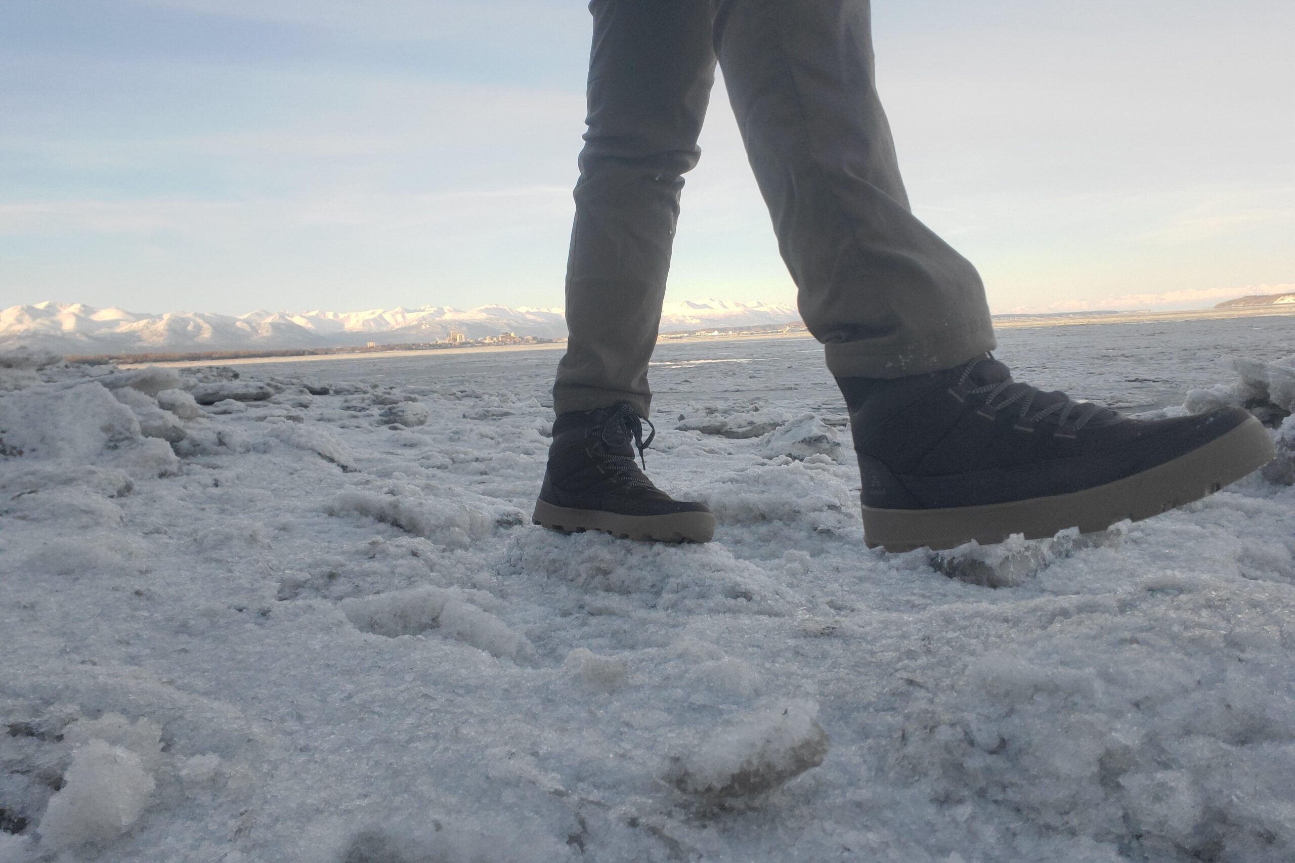 A man walks on an ice covered shoreline.