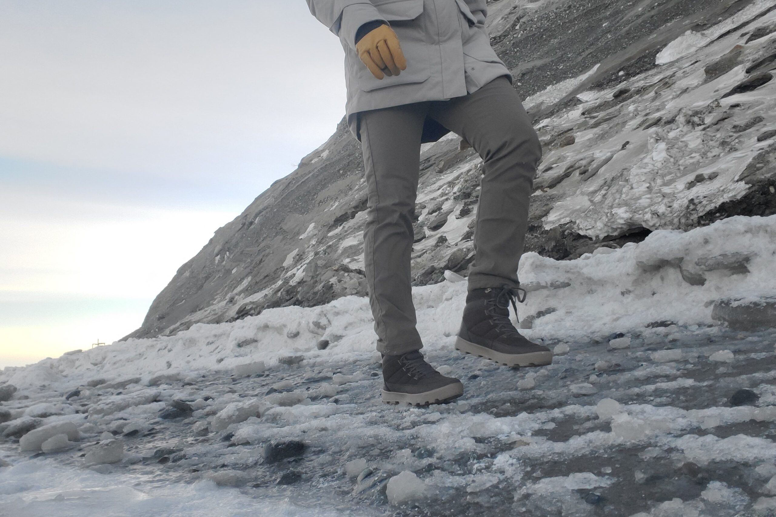 A man walks along an icy slope in winter clothes/