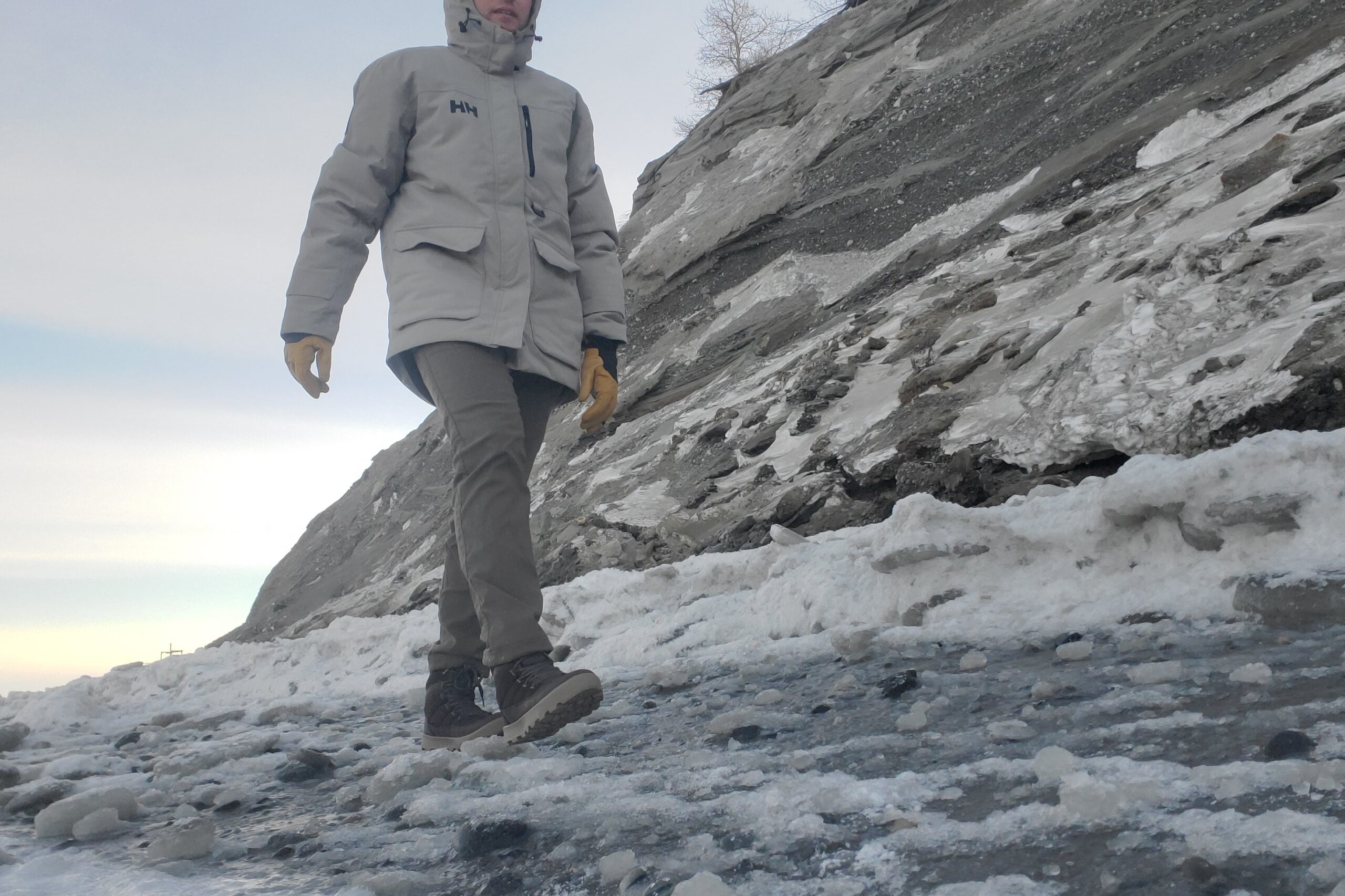 A man walks along an ice covered beach