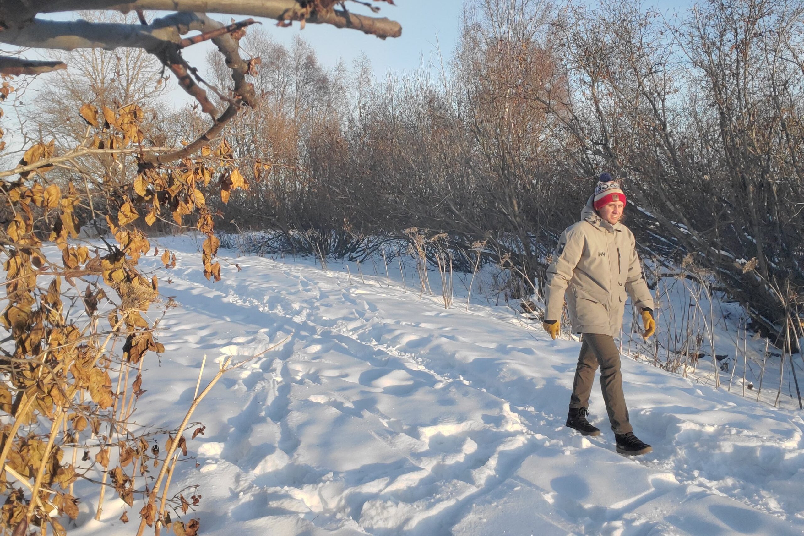 man walking on a snow covered road on a sunny day wearing the helly hansen urban lab parka