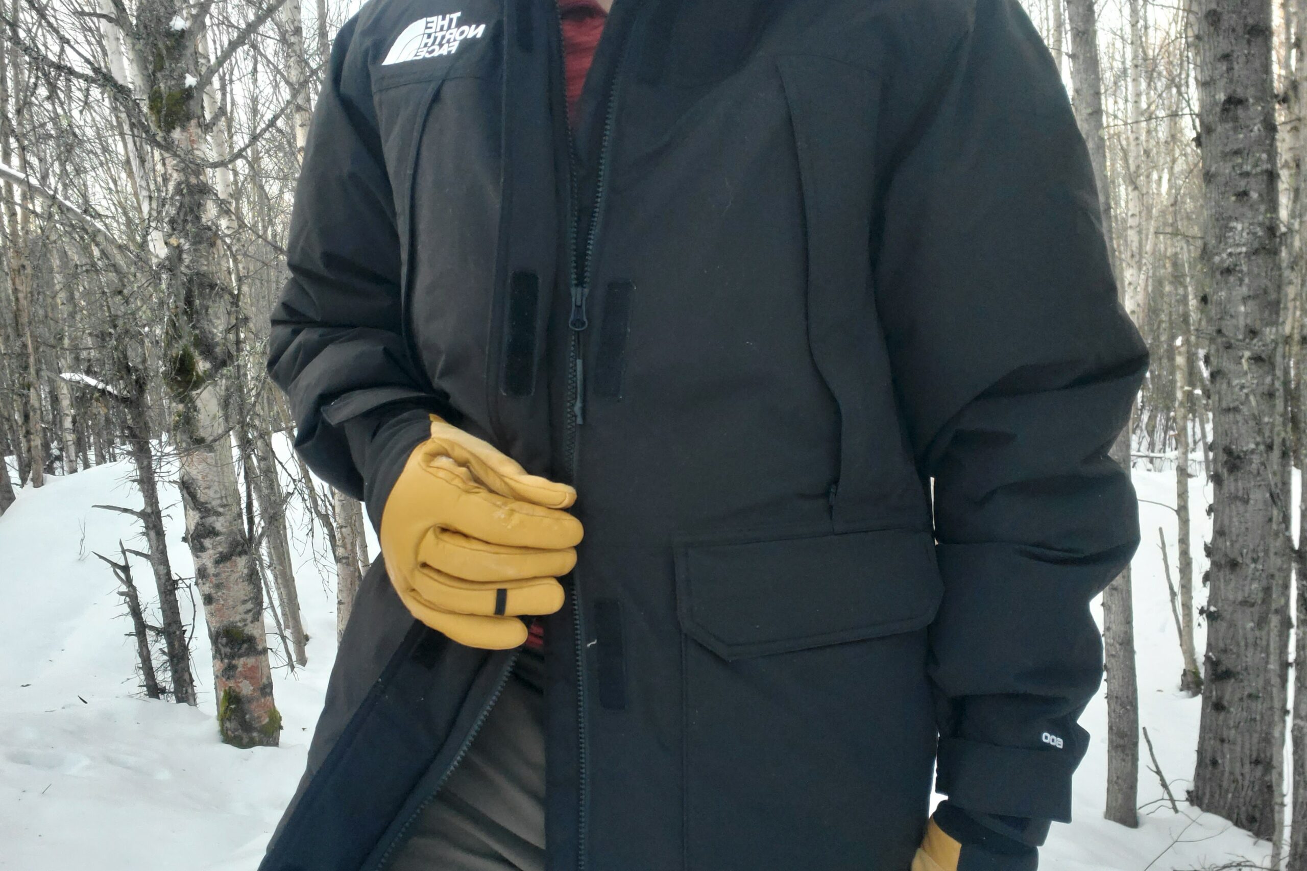 A man shows a double zipper on a black jacket.