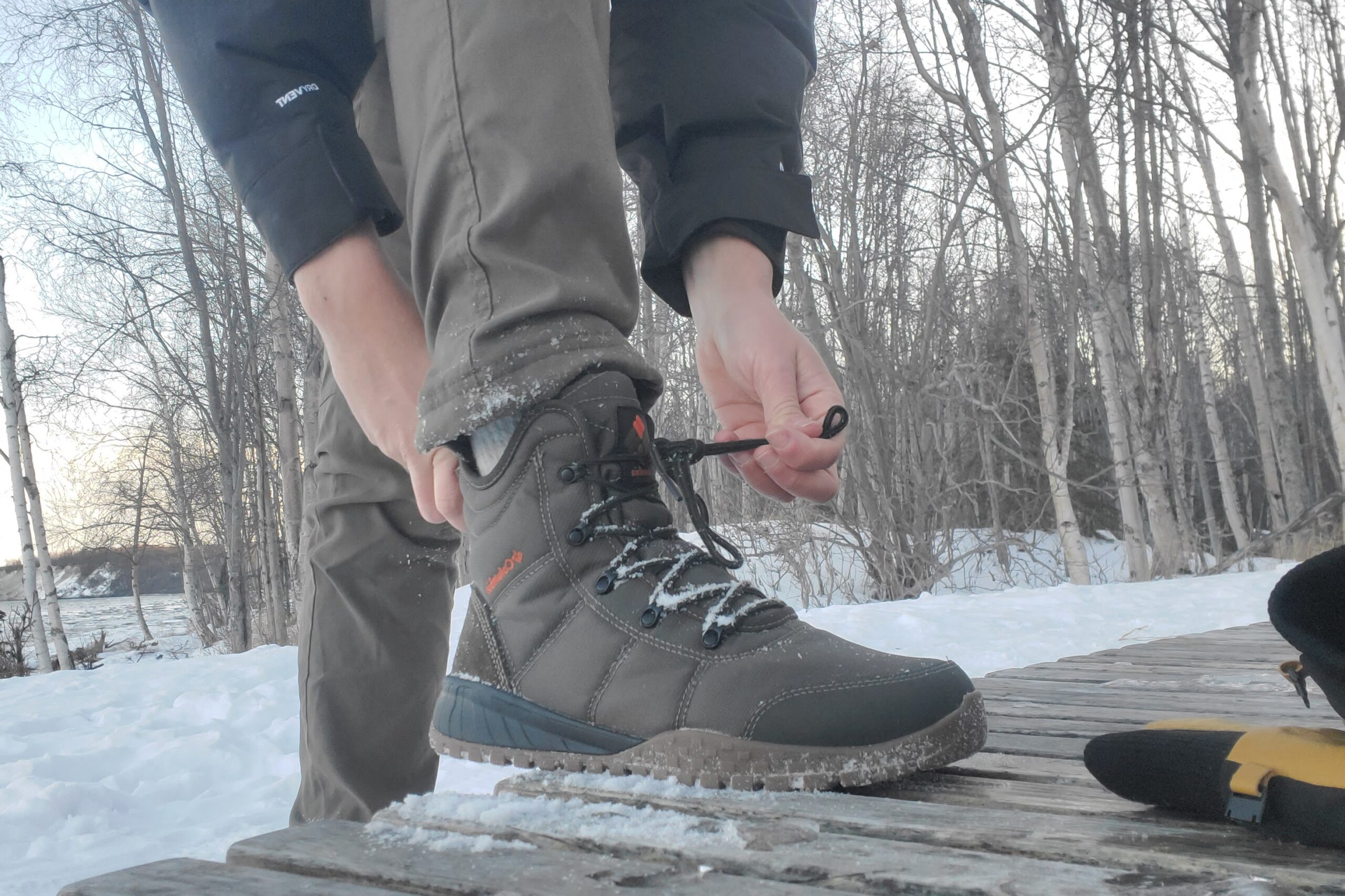 A man tightens the laces around his snow boots.