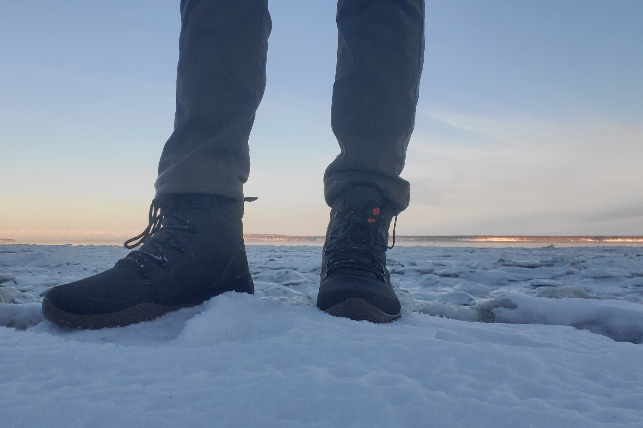 A man stands on an ice shelf along the ocean.