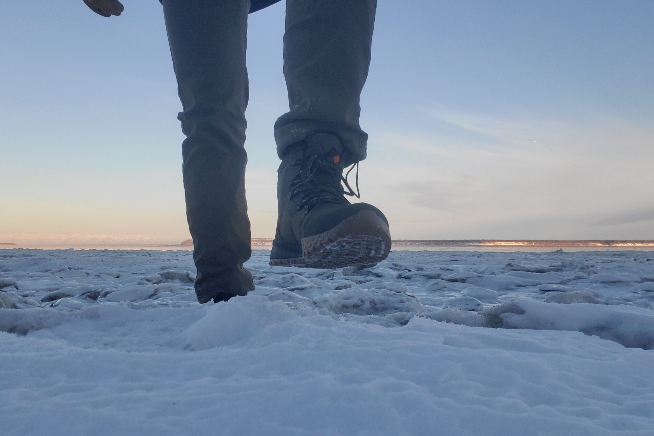 A man steps up on a snowy step showing the boot's tread.