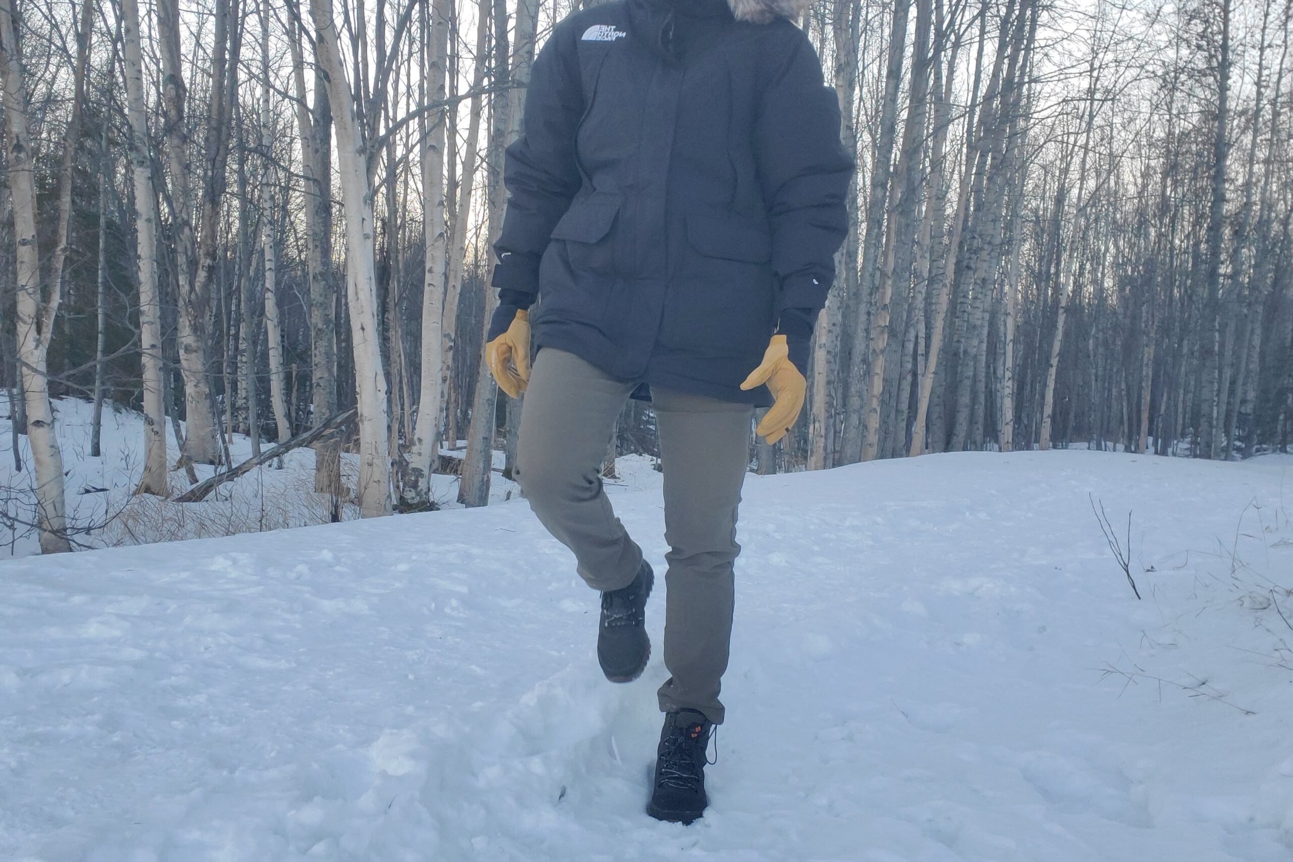 A man walks down a snow covered trail.